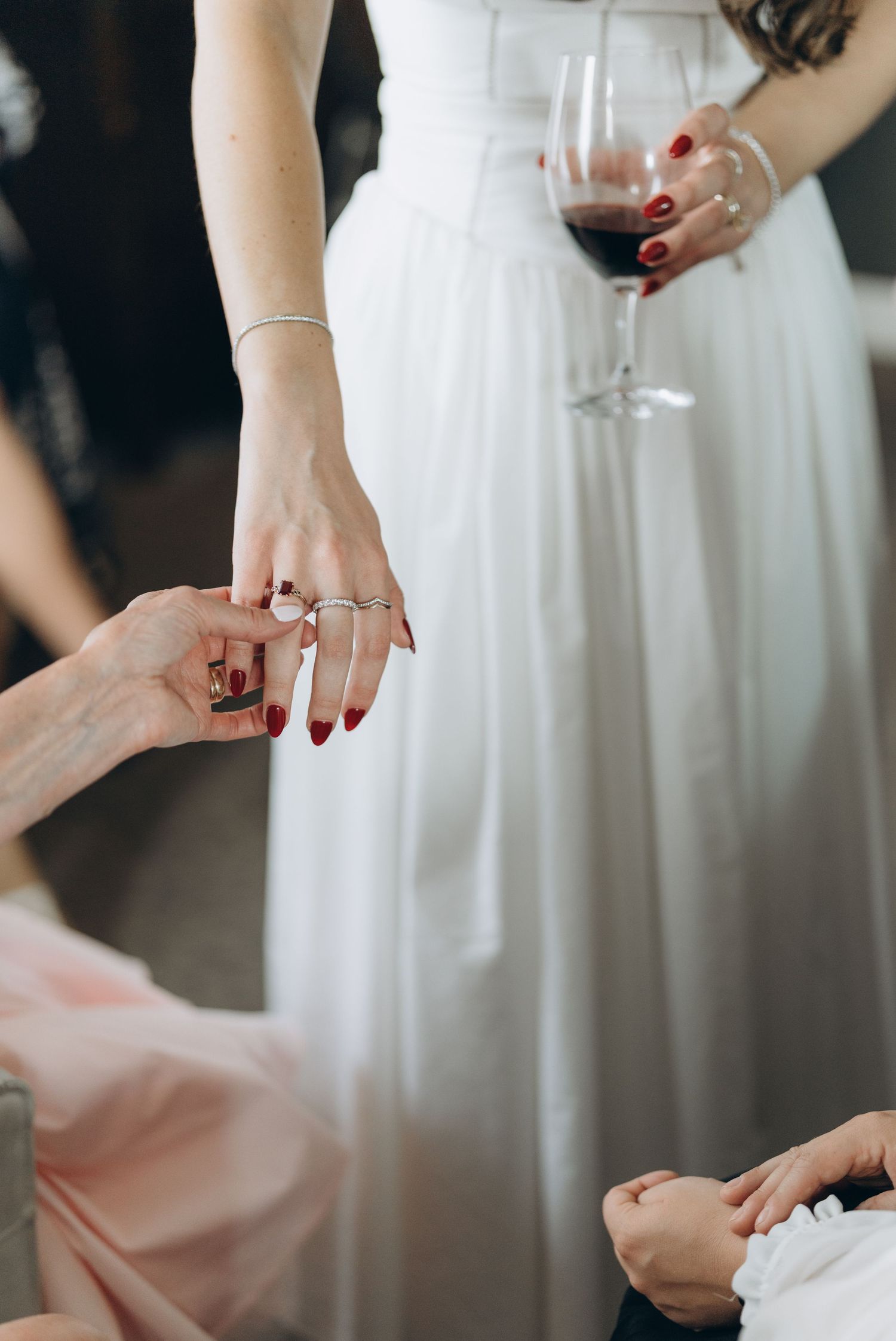 Close-up of hands exchanging wedding rings during an intimate ceremony with red nail polish.