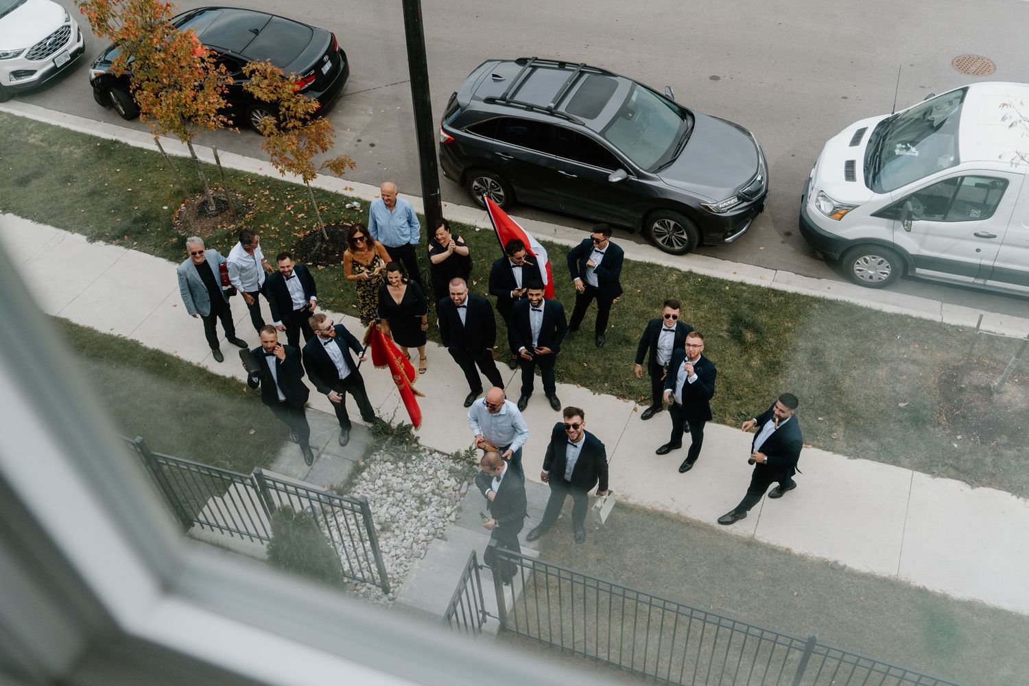 A group of people walking along a sidewalk on a cloudy autumn day, viewed from above.