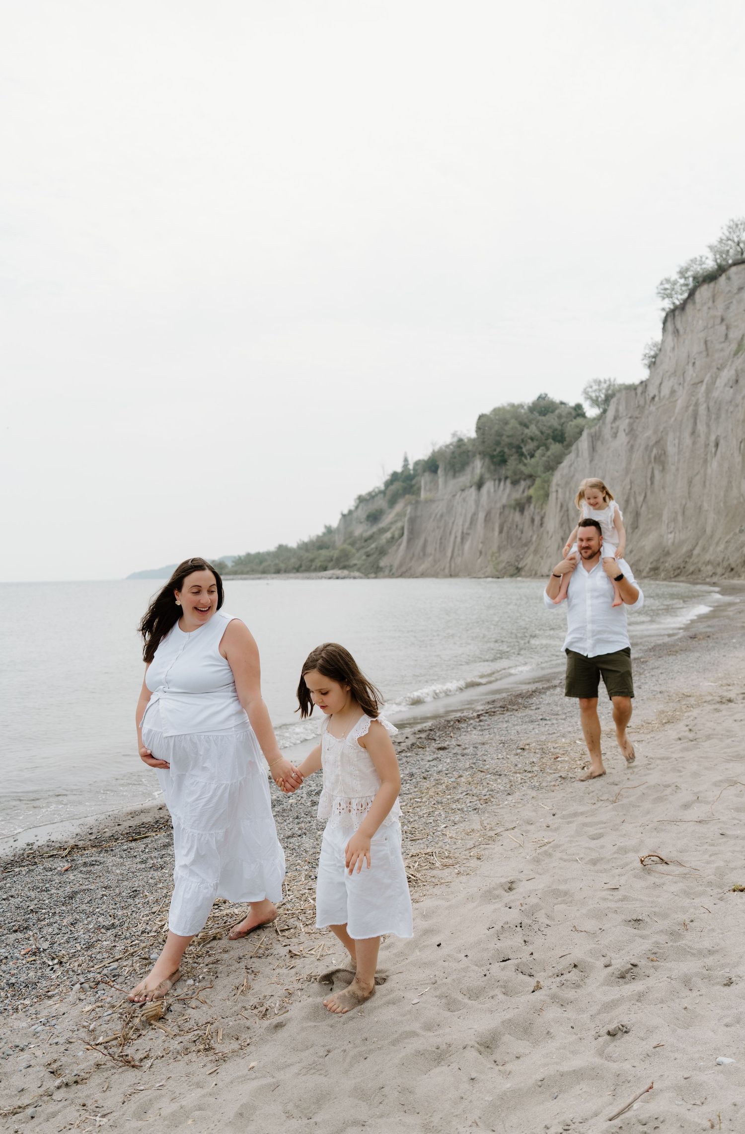 Couple enjoying playful moments along a rocky beach with cliffs in the background, photographed in sequence.