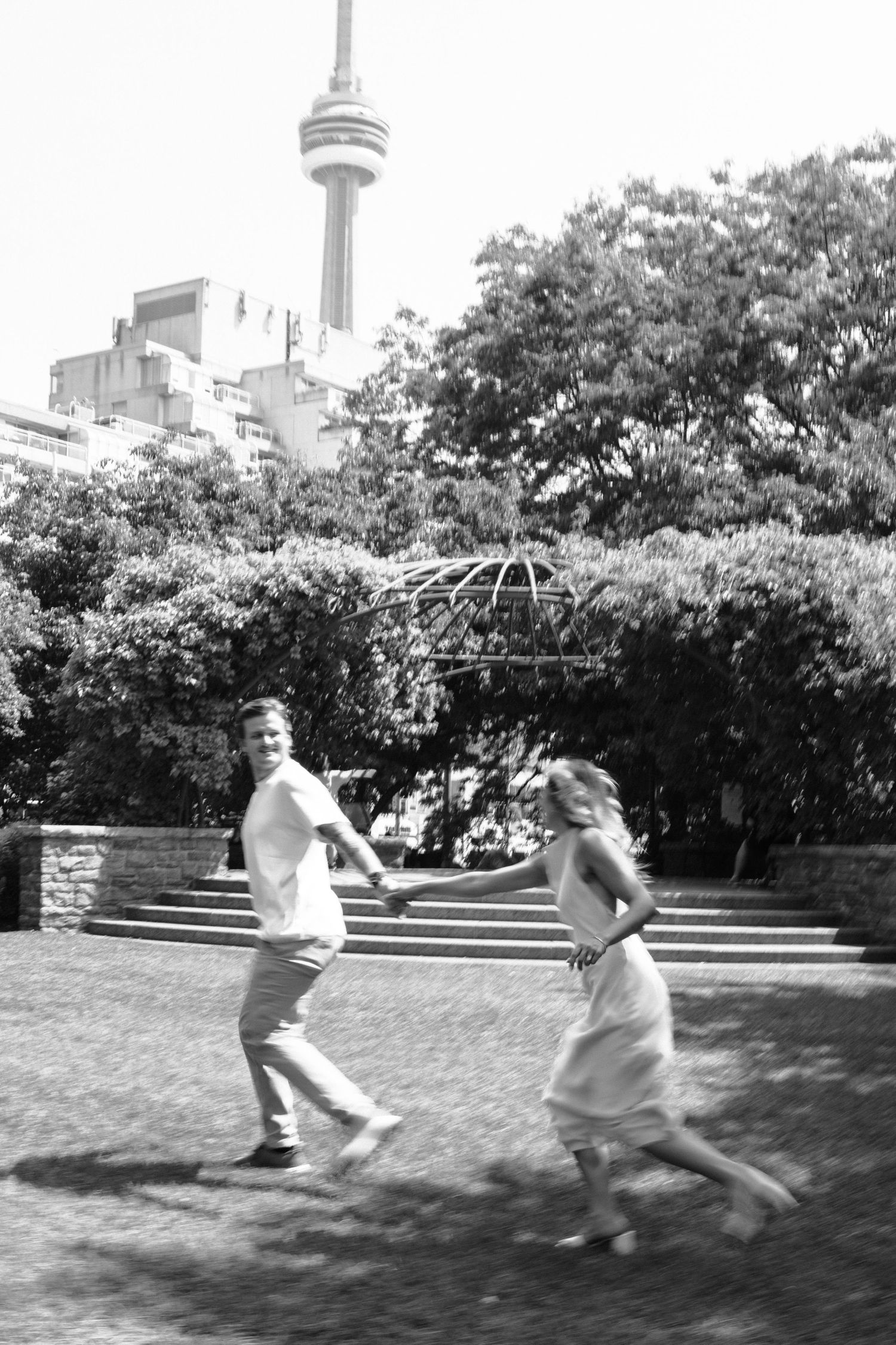 Motion blur sequence of two people spinning and dancing together in an outdoor garden patio area with trees and bushes.