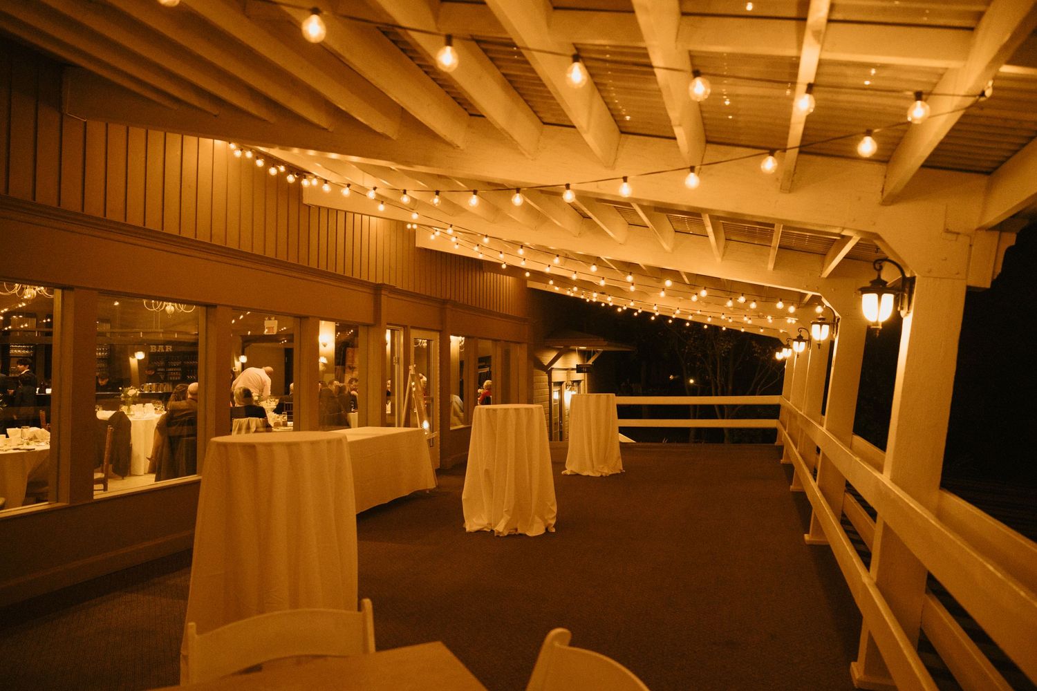 Reception venue with string lights and white tablecloths creating romantic ambiance.