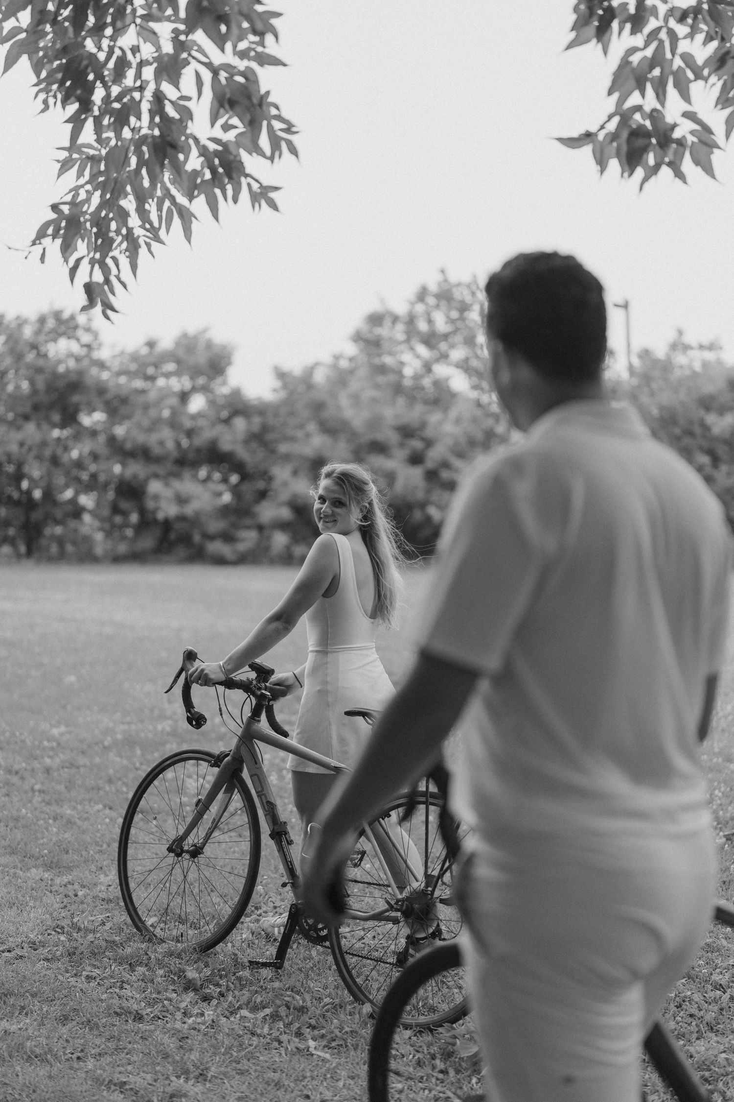 Black and white photo collage of two cyclists on a path having a conversation next to trees.
