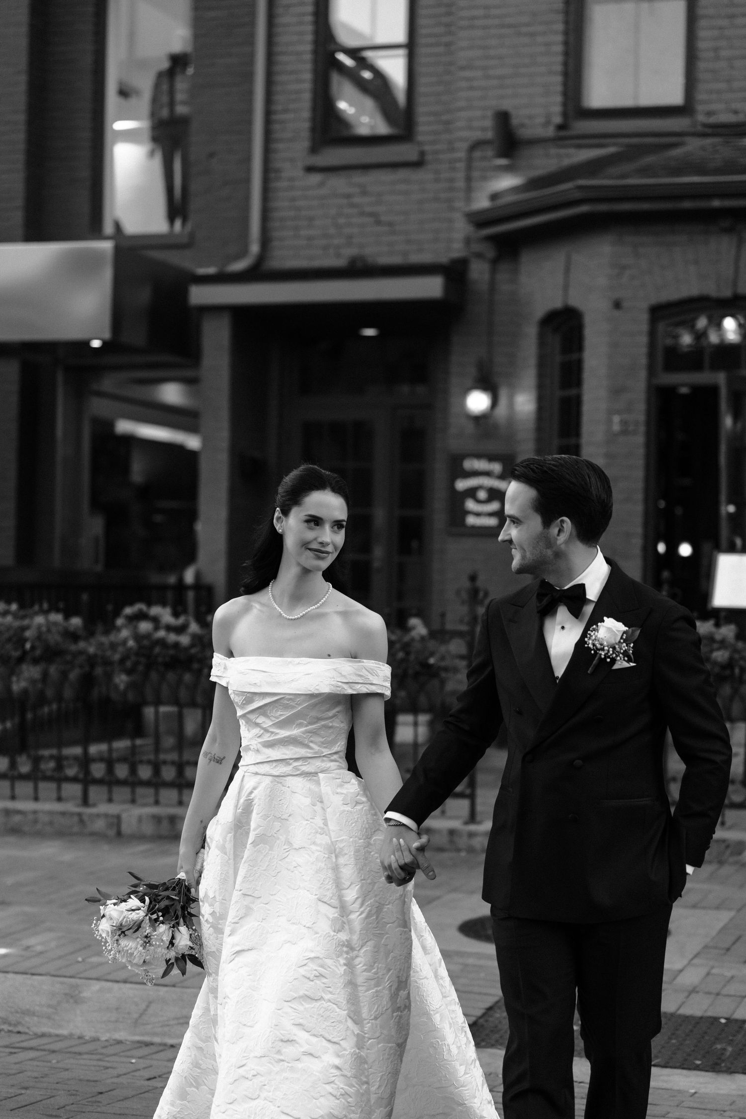 A black and white wedding photo series showing a couple walking together on a city street.