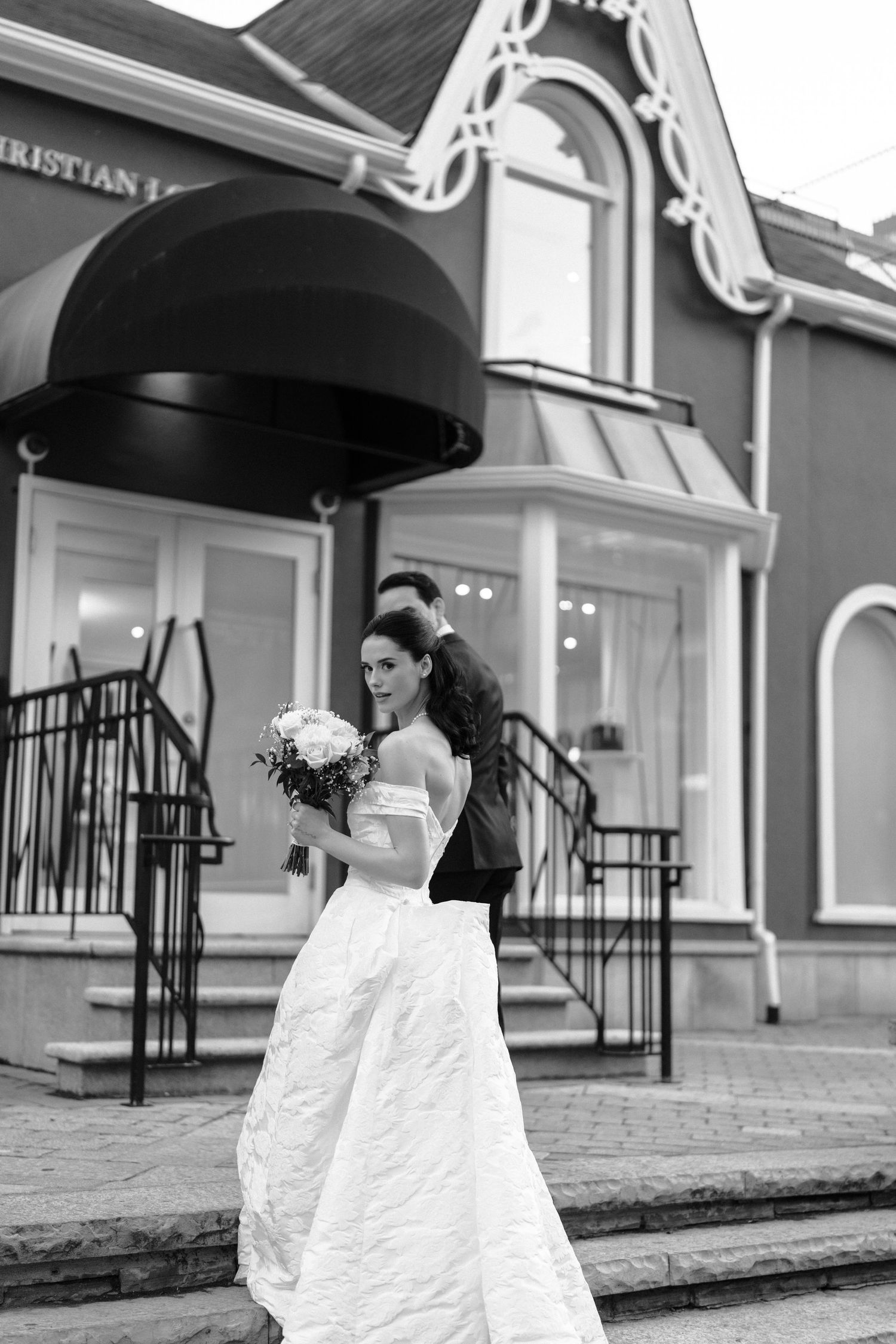 Black and white photo sequence of newlyweds dancing joyfully outside a building with ornate architecture.