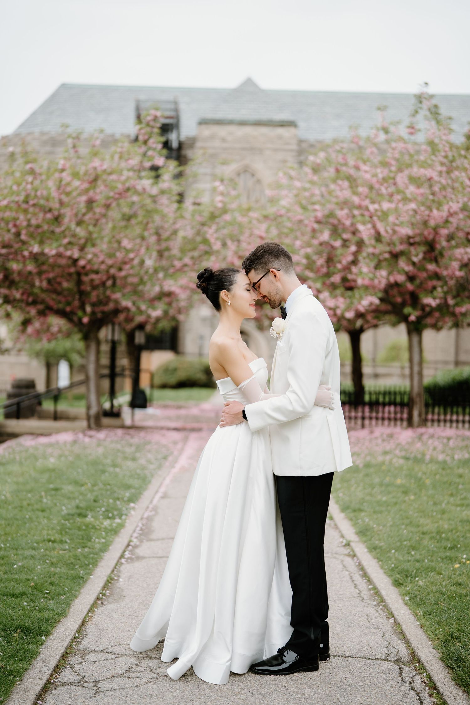 Newlyweds share intimate moment on garden path lined with spring blossoms.