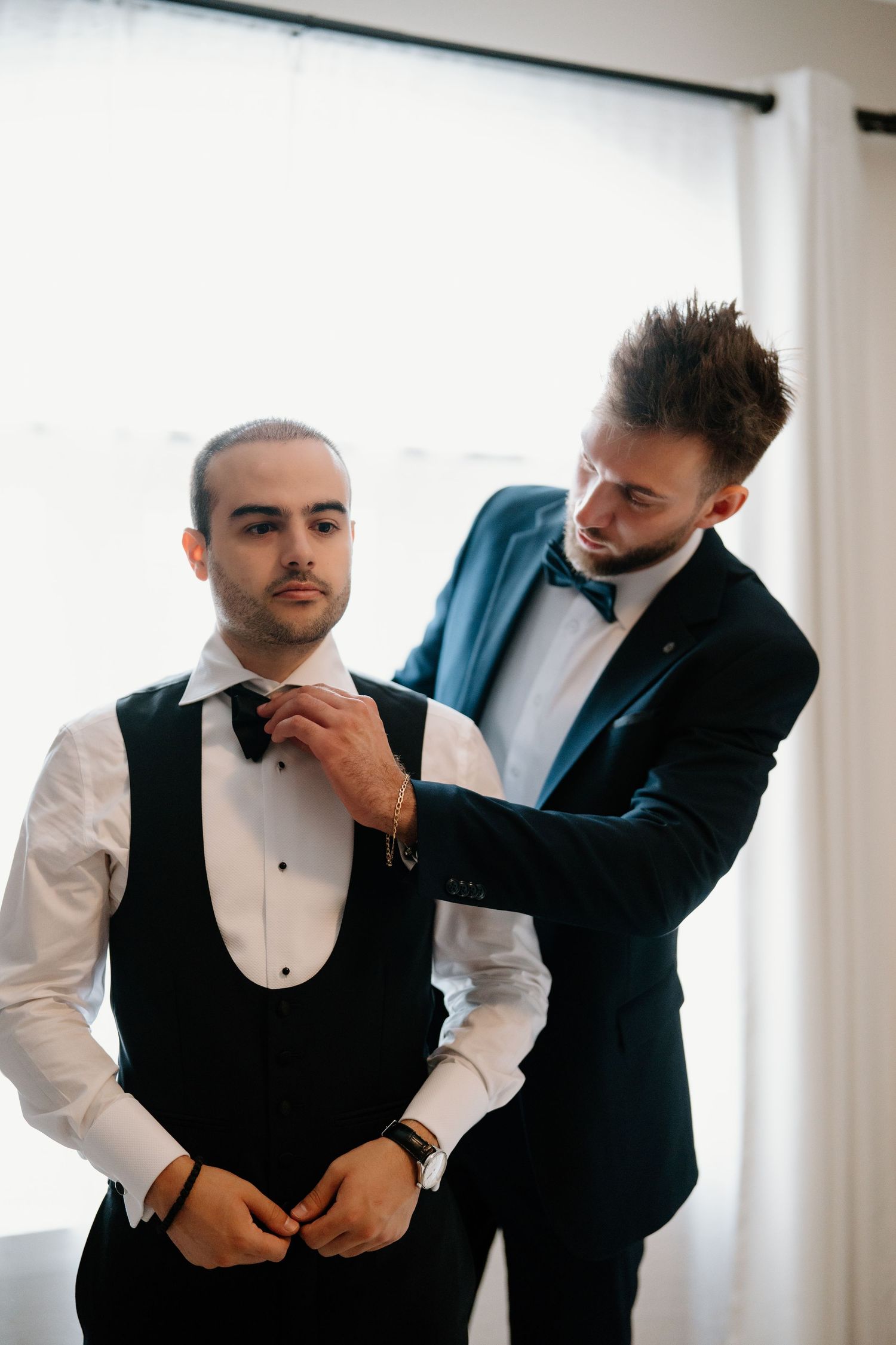A series of photos showing a groom getting ready with help adjusting his bow tie and vest before the wedding ceremony.