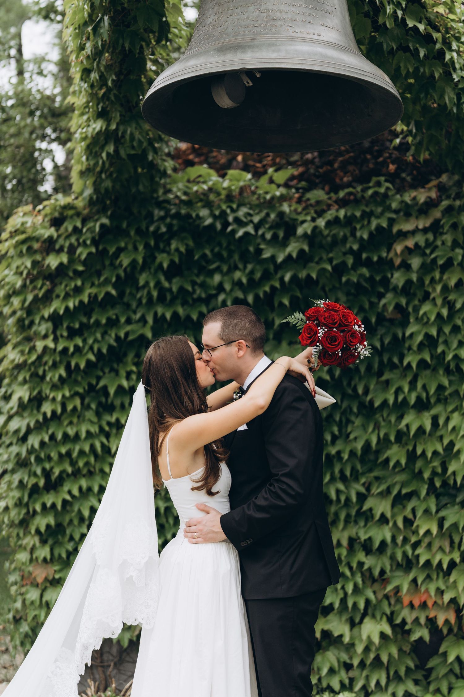 A romantic wedding series showing a couple in front of an ivy wall sharing sweet kisses and embraces.