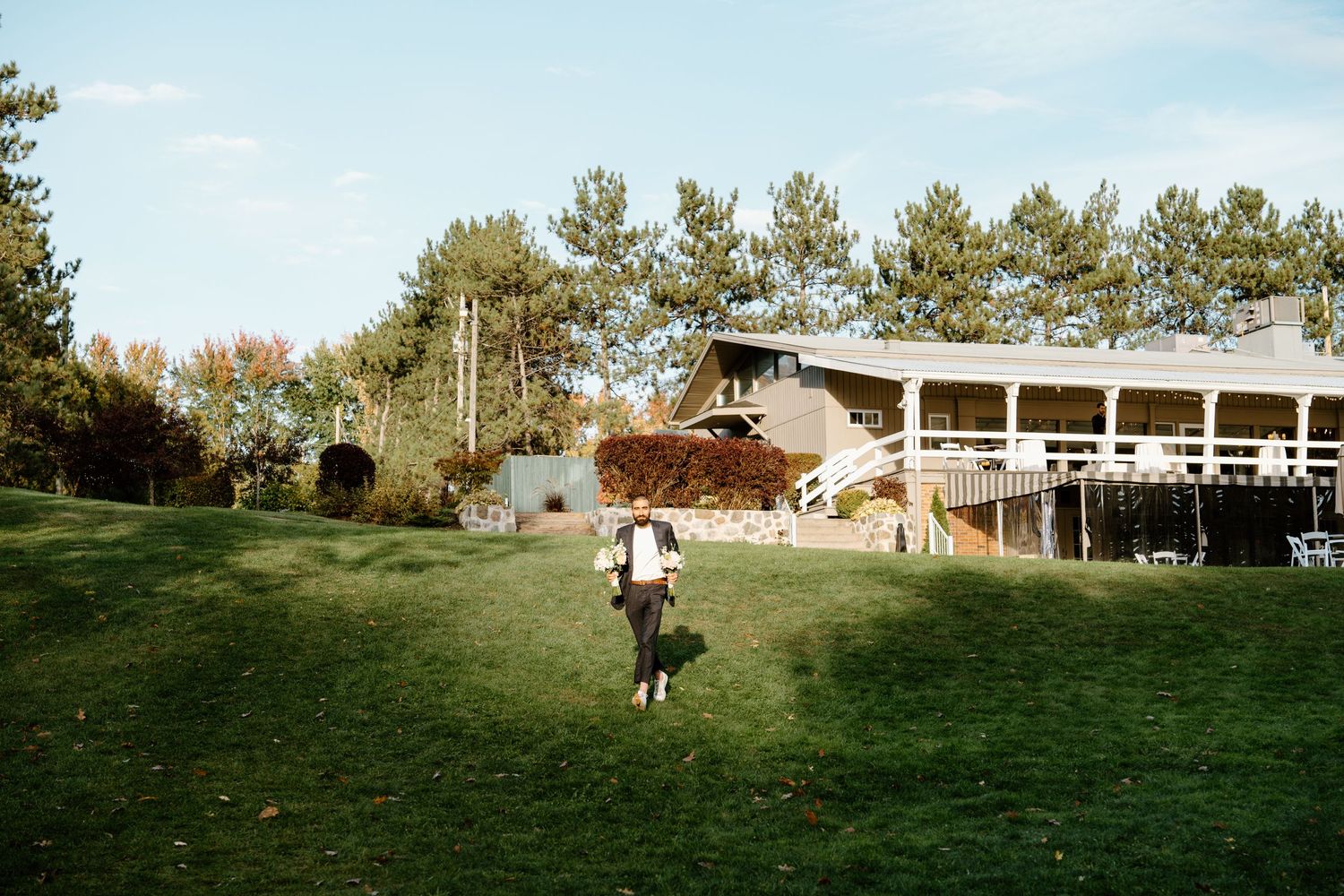 Large building with wooden deck visible across a grassy lawn on sunny day.
