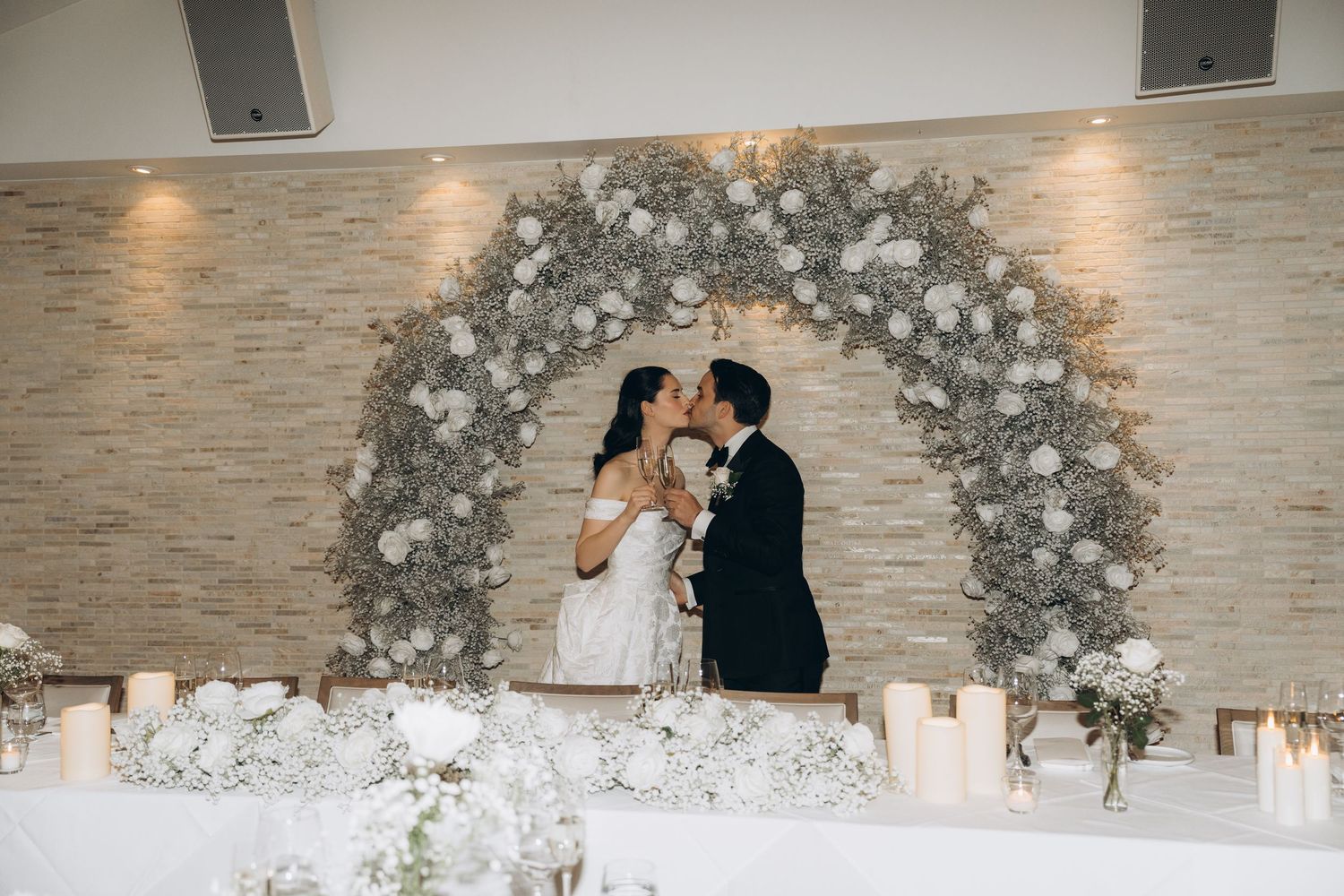 A romantic wedding ceremony sequence showing a couple exchanging vows under a white floral arch in an elegant venue.