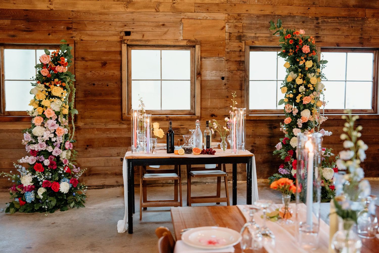 Rustic wooden barn interior decorated with floral arrangements and windows creating a charming wedding venue.