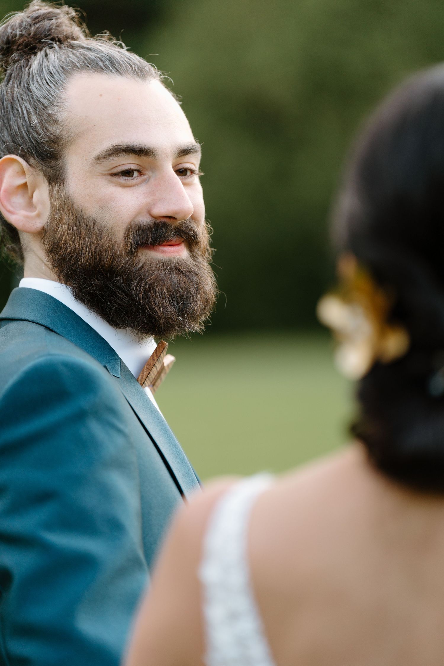 Wedding scene showing groom in teal suit with full beard.