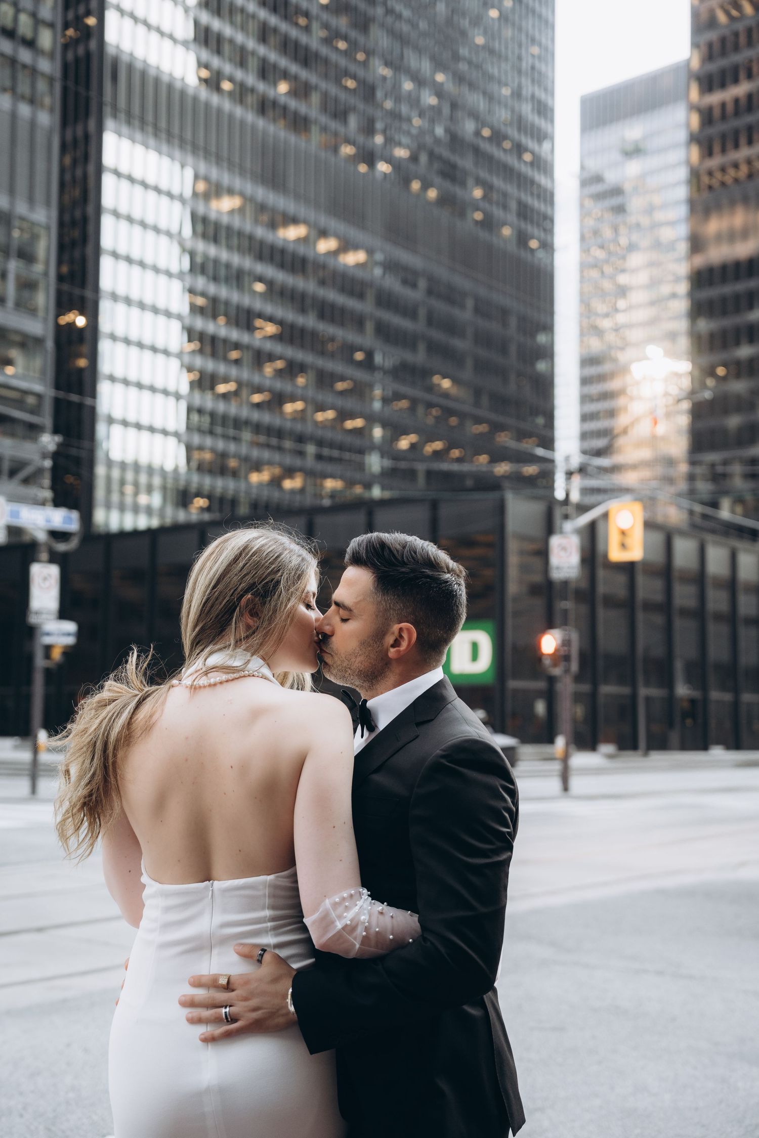 A romantic moment between a couple on a city street with modern glass buildings in the background.