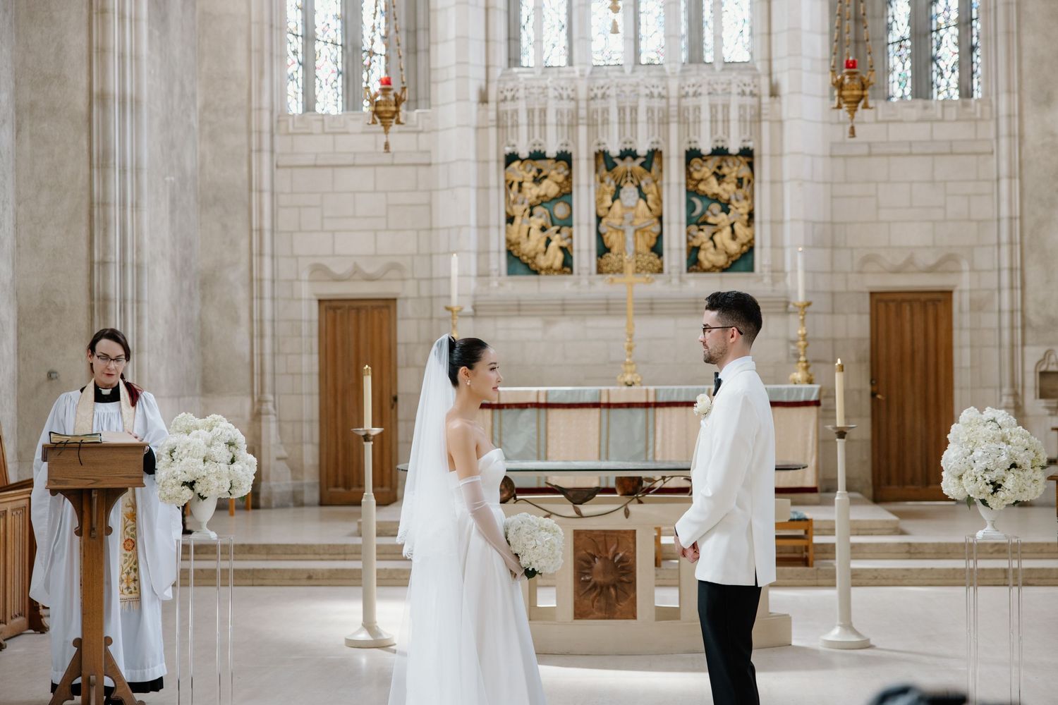 Elegant church interior with ornate gothic architecture and stained glass windows during a traditional wedding ceremony.