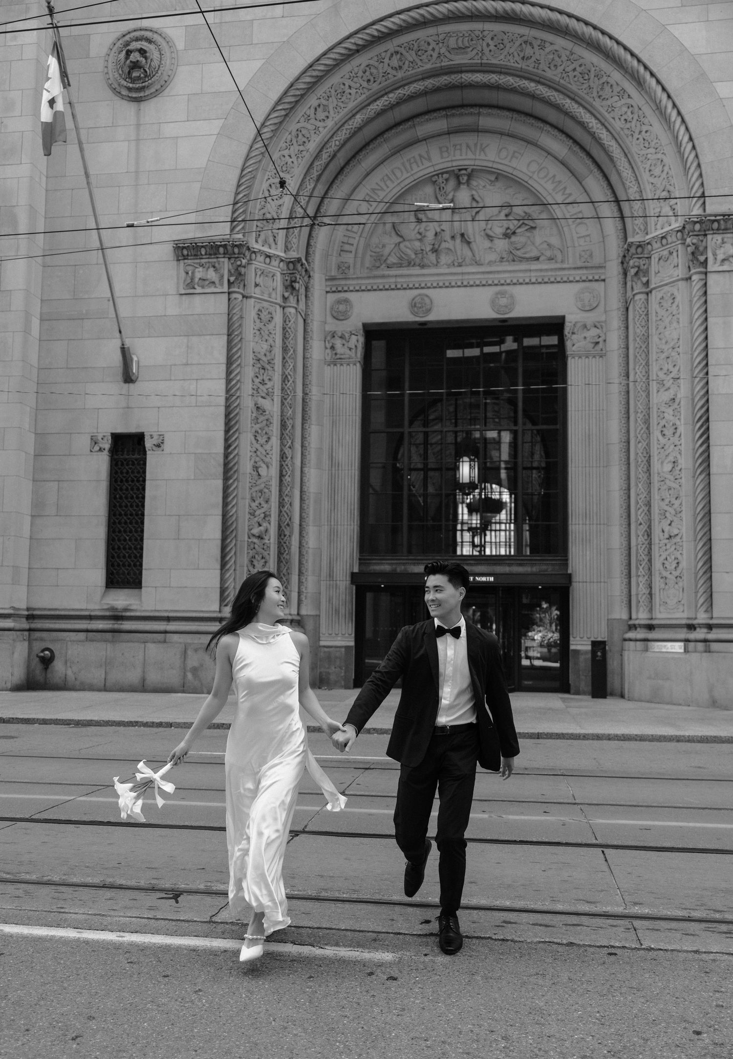 Black and white series of photos showing a couple walking and dancing in front of an ornate building entrance.