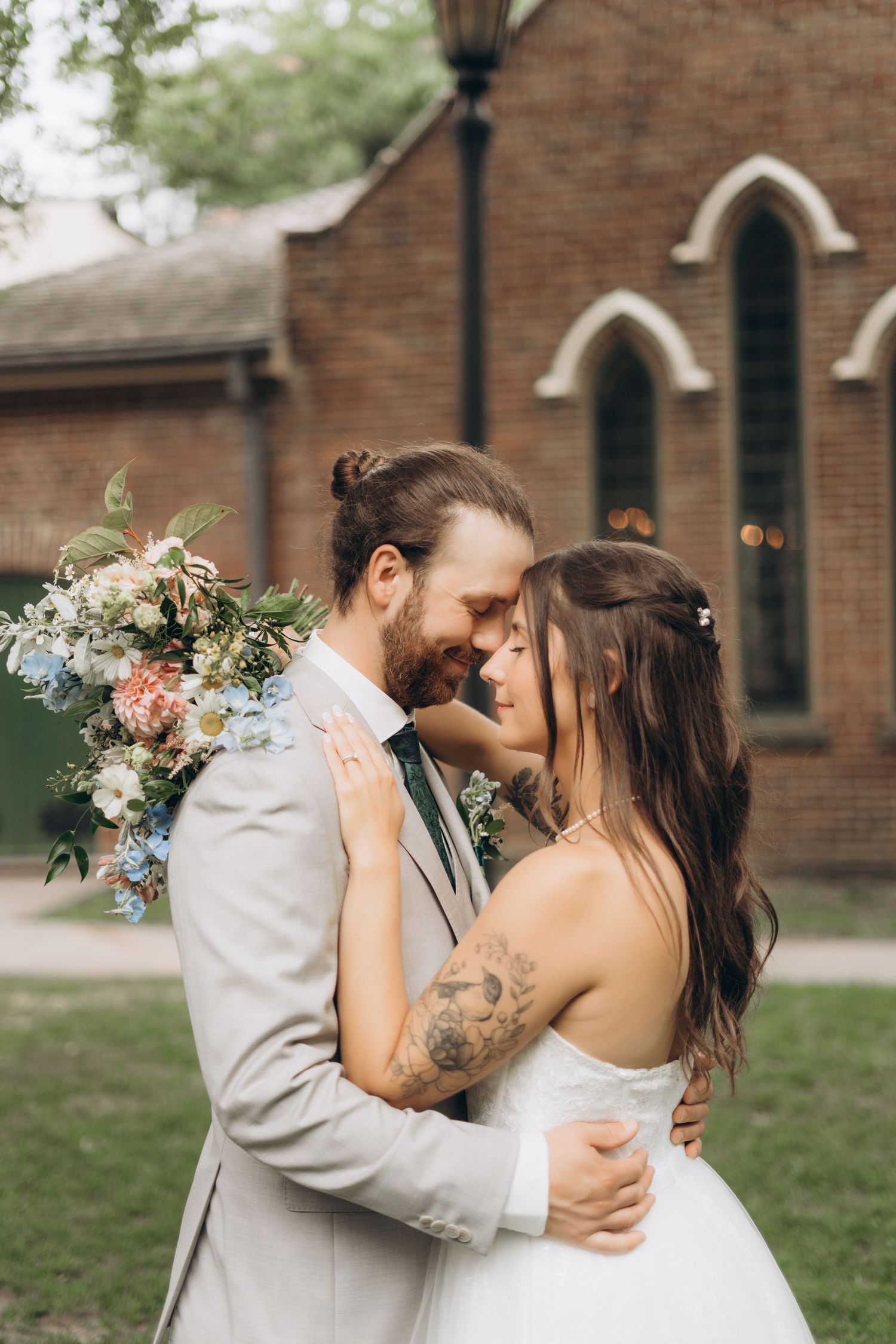 A romantic wedding couple shares intimate kisses in a series of outdoor portraits against a brick church backdrop.