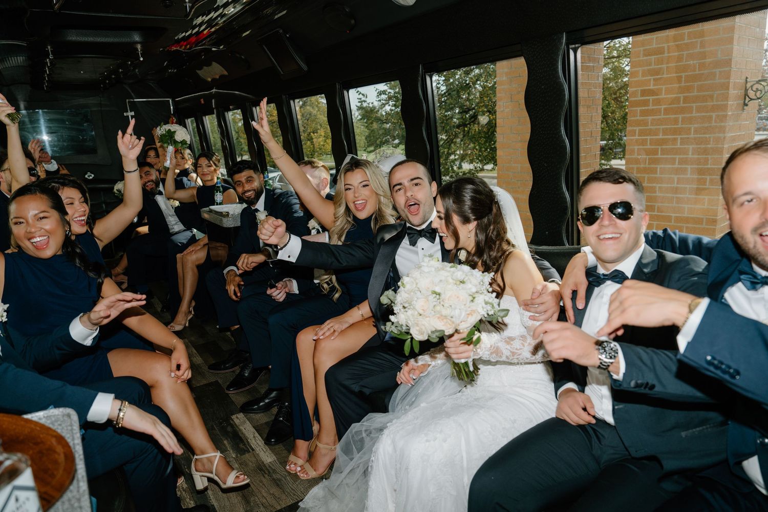 Wedding guests sit on wooden benches during an outdoor ceremony in a natural setting.