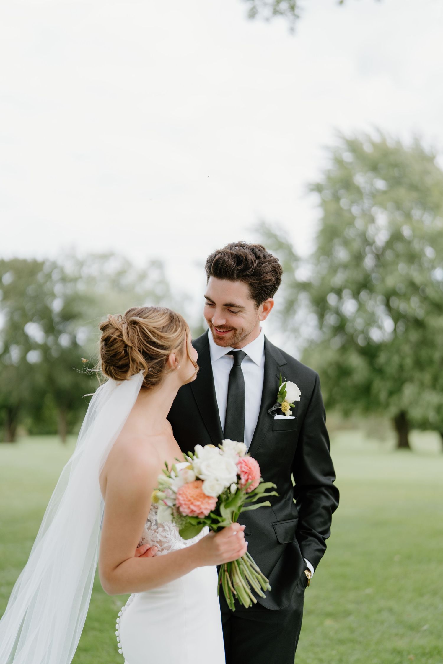 Newlywed couple shares intimate moments on a green lawn during their outdoor wedding photoshoot.