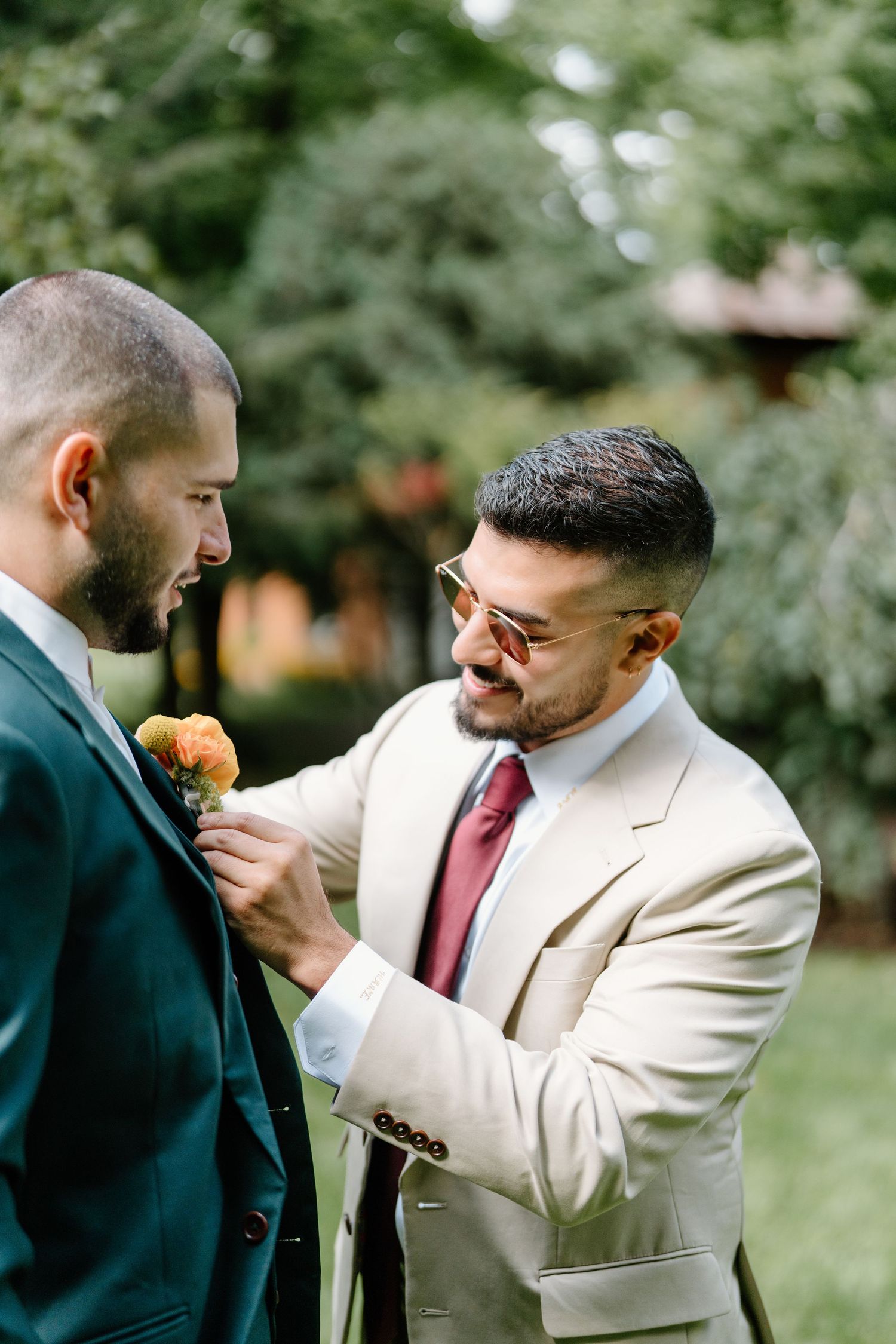 Two men in contrasting suits share an emotional embrace during what appears to be a wedding ceremony.