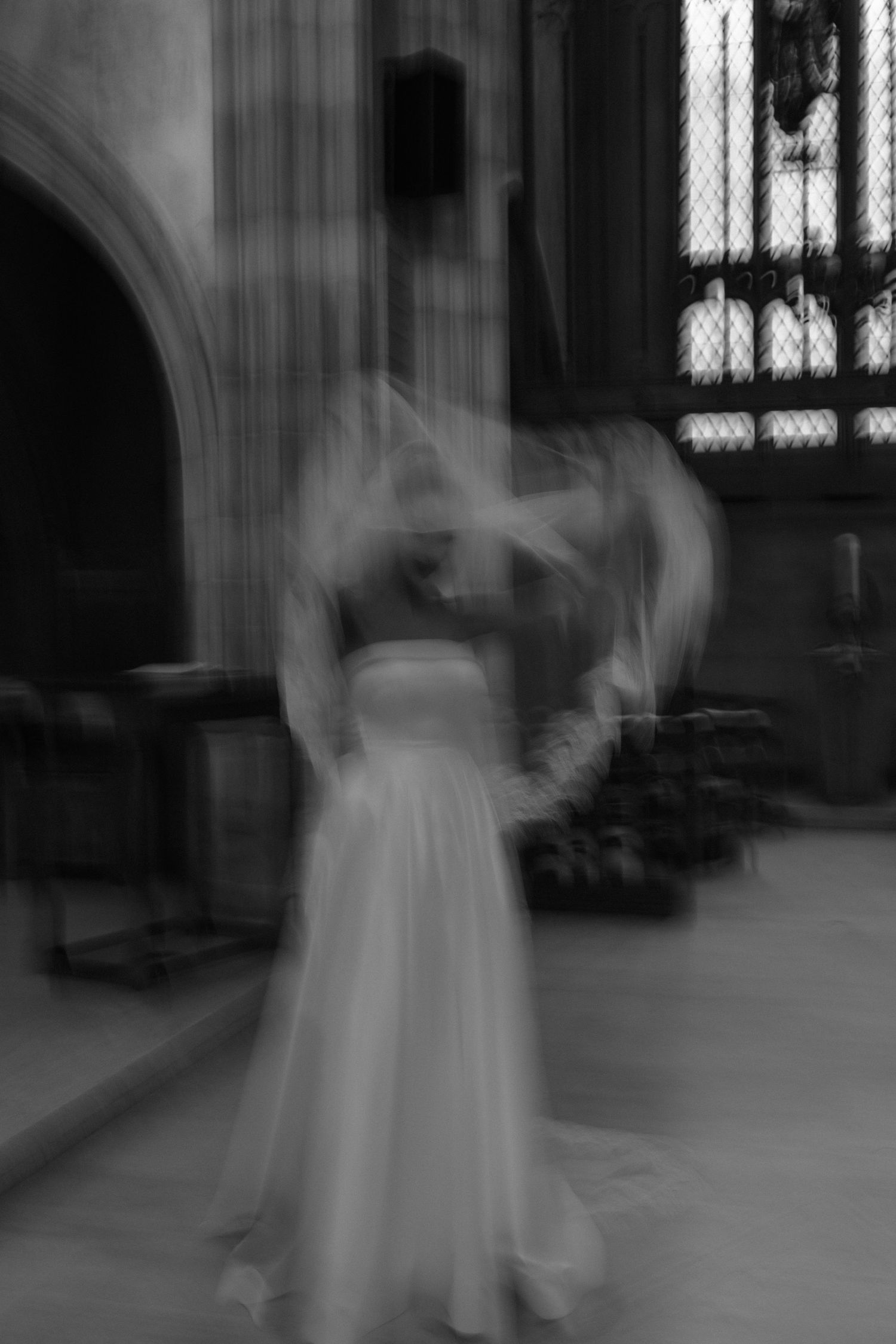 A ghostly figure in a white dress appears as a blurry, ethereal form inside a gothic church interior.