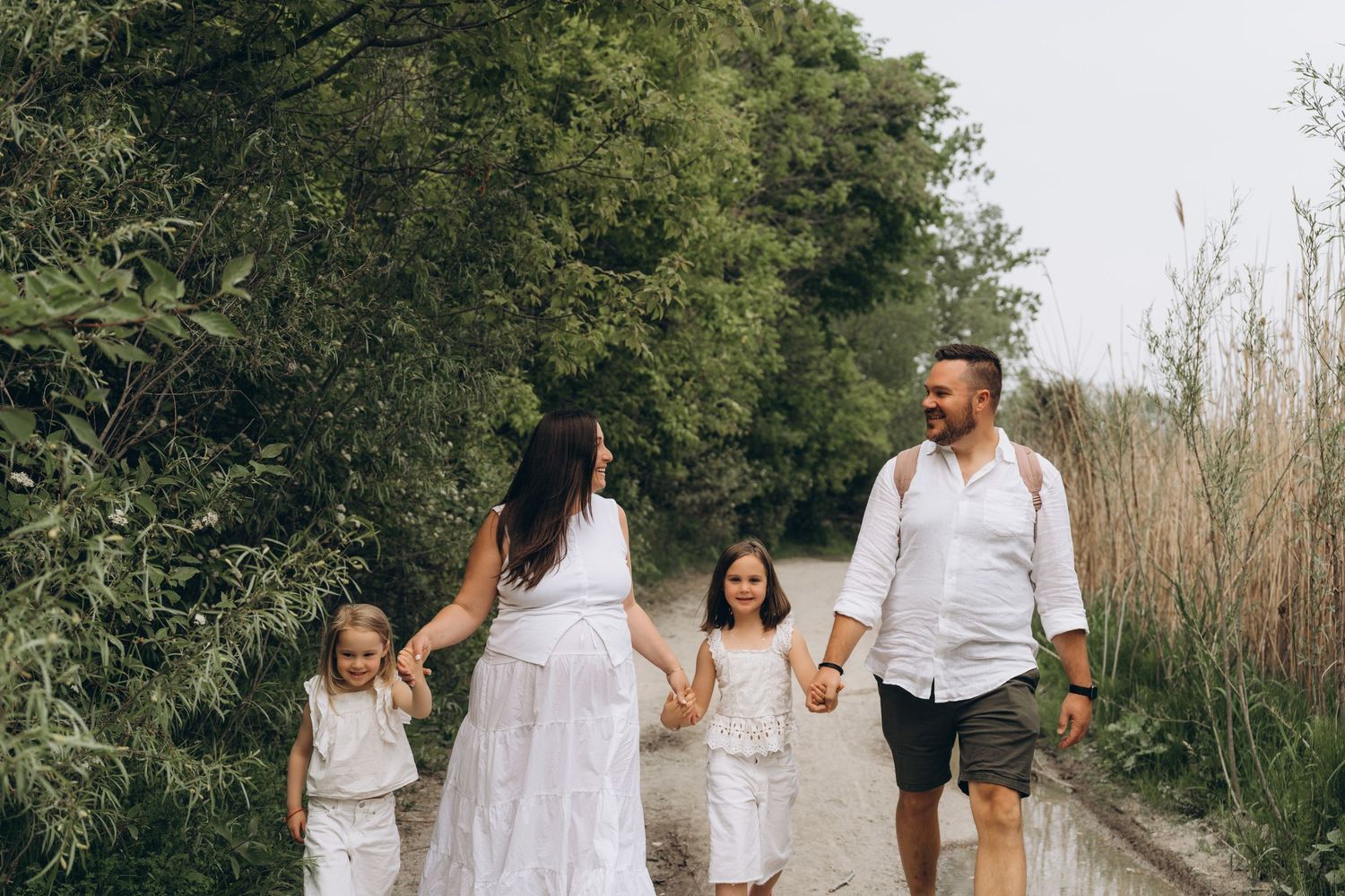 A joyous family walking on a nature path together while holding hands and enjoying quality time outdoors.