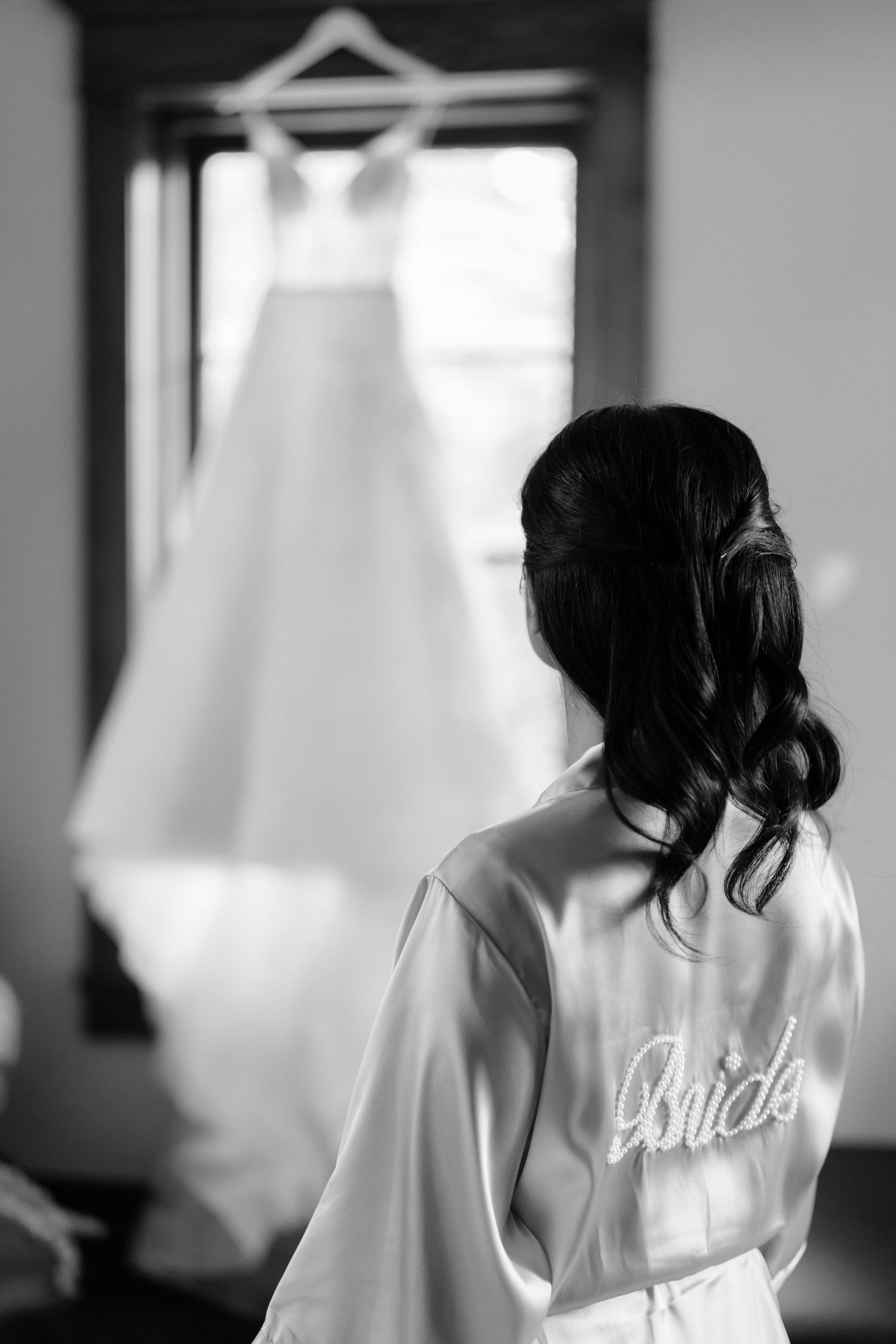 Black and white photo series showing a bride in a white robe getting ready on her wedding day.