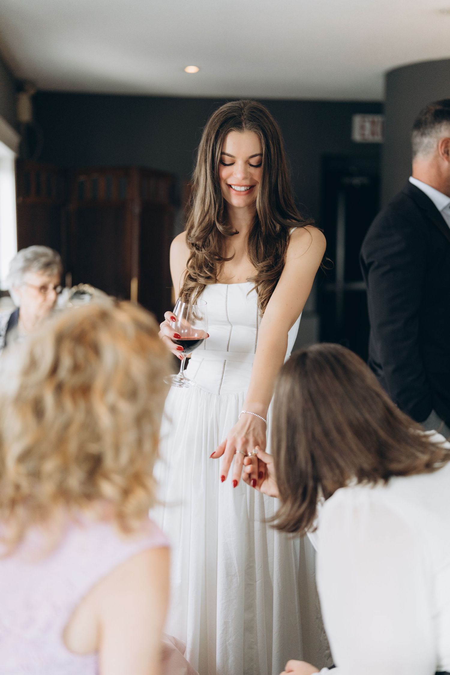 Bride in white gown shares a joyful moment with small attendants dressed in white during wedding preparations.