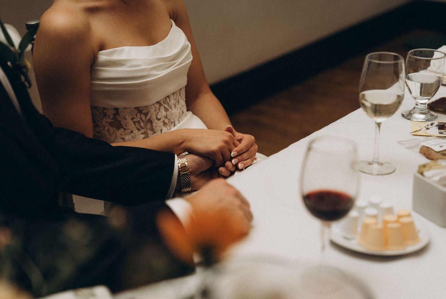 People dining at a restaurant table with wine glasses and place settings in a dimly lit setting.