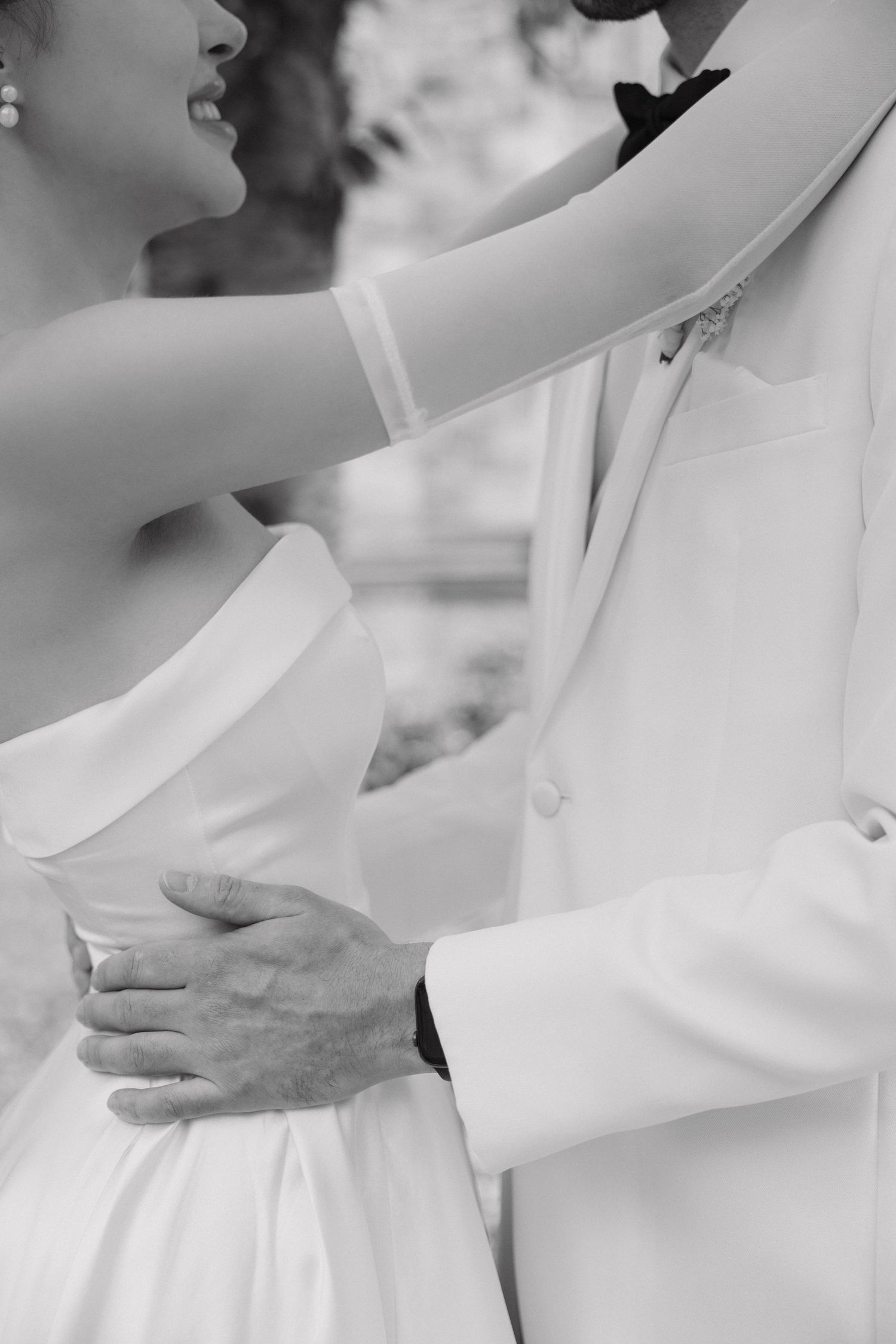 An intimate black and white wedding photo showing the bride in a strapless gown dancing with the groom in a white suit.