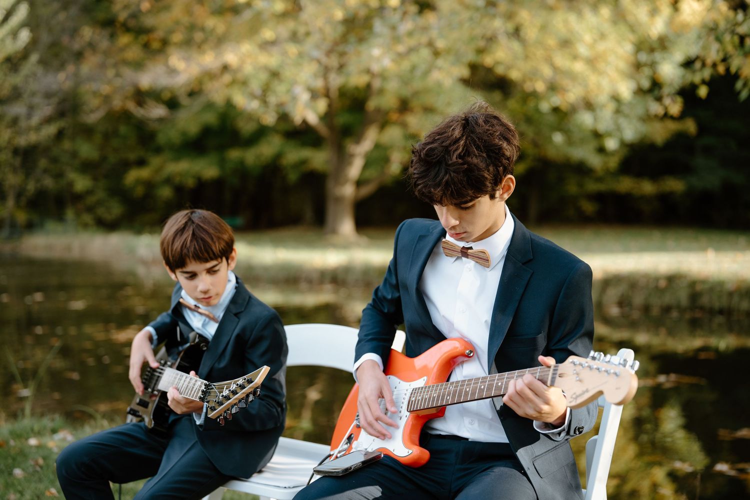 Musicians performing on guitars during an outdoor autumn event.