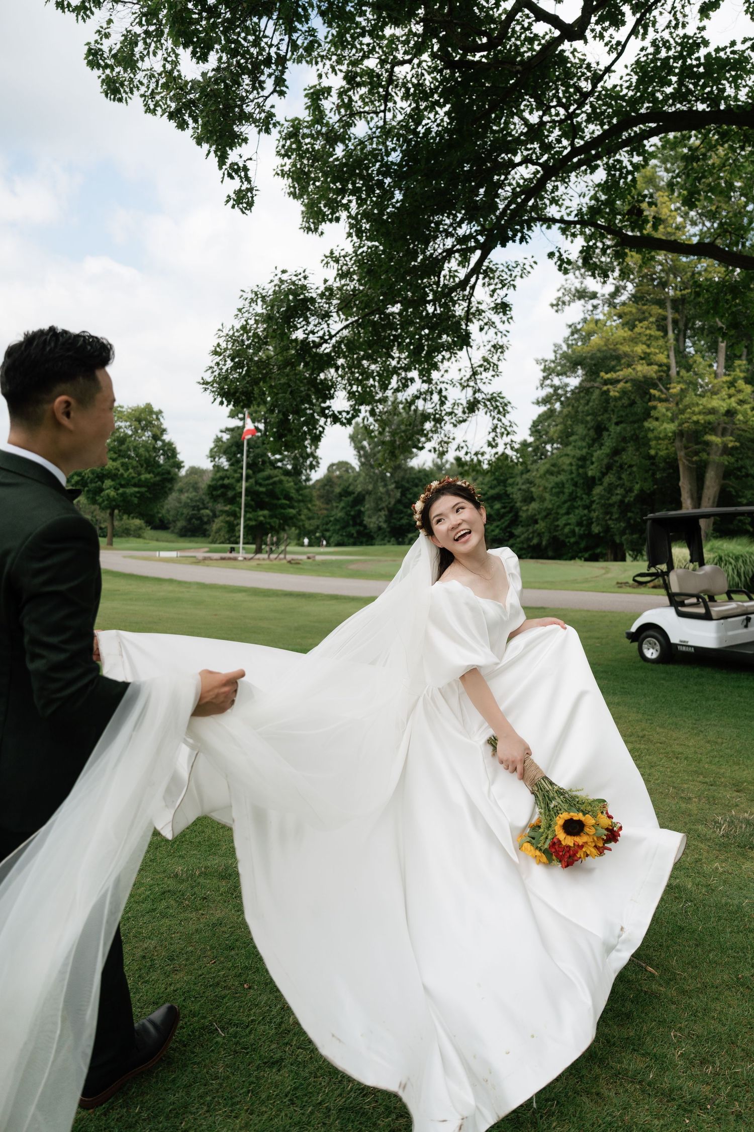 Newlyweds playfully chasing each other on the lush green golf course at Pheasant Run, captured by AZ Photo Studio.