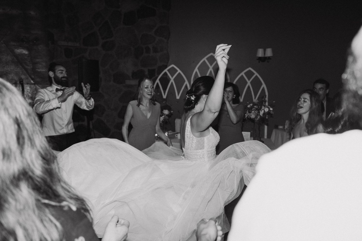 Wedding guests dancing and celebrating on a dimly lit dance floor at a reception venue.