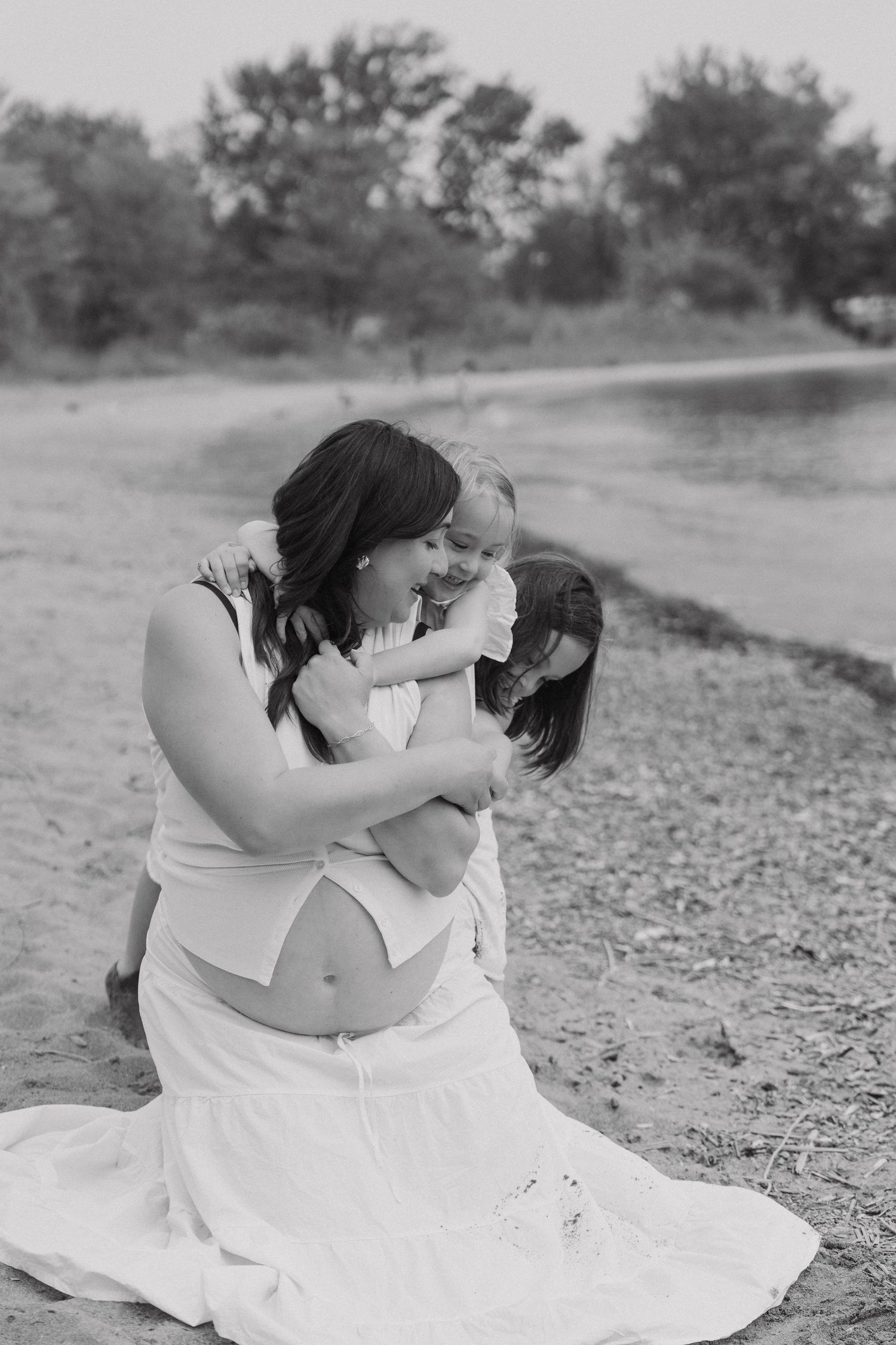 A tender black and white portrait of affection between parent and infant on the shore of a peaceful lake.