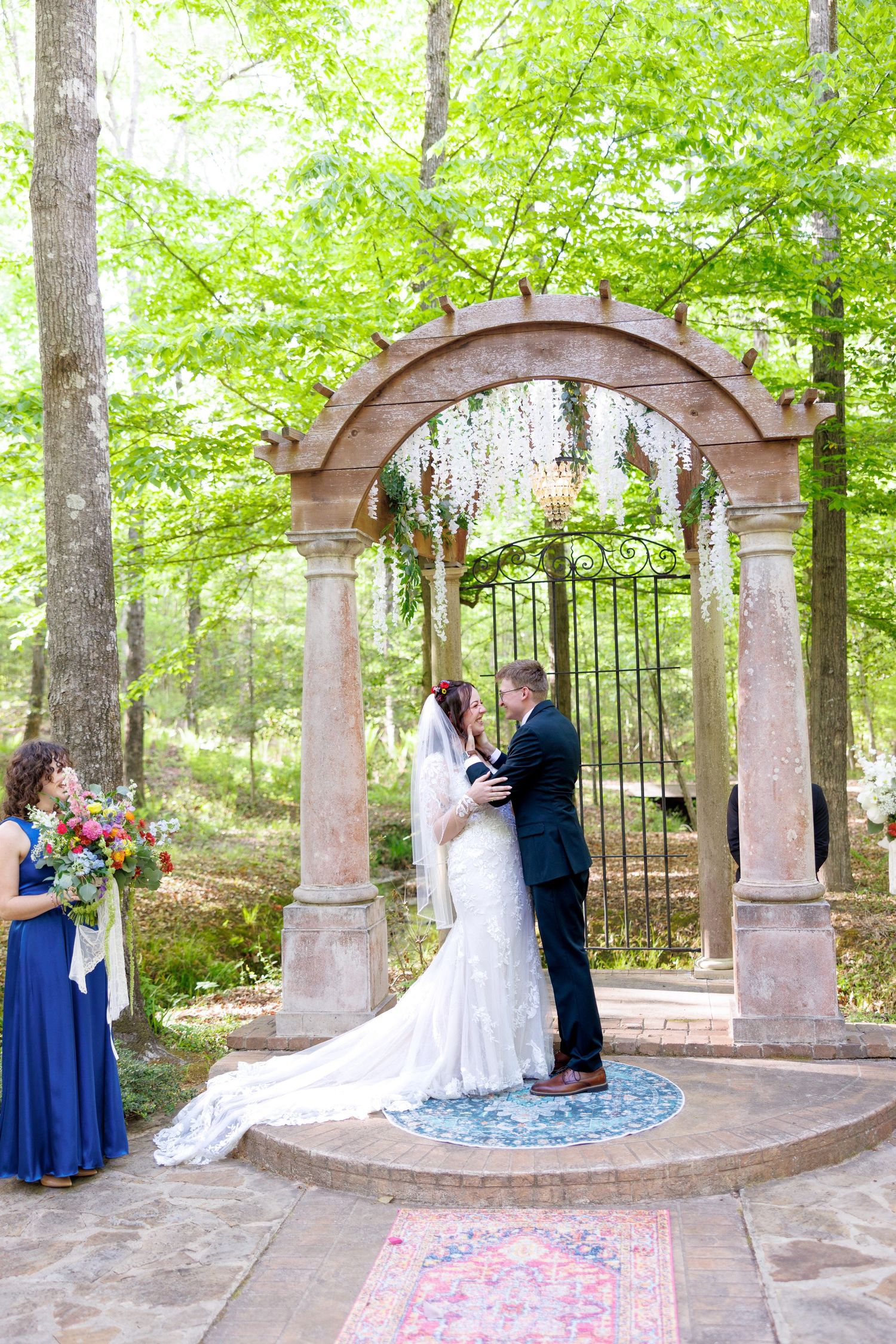 Bride and groom exchange vows under stone arch in enchanting woodland outdoor wedding ceremony.