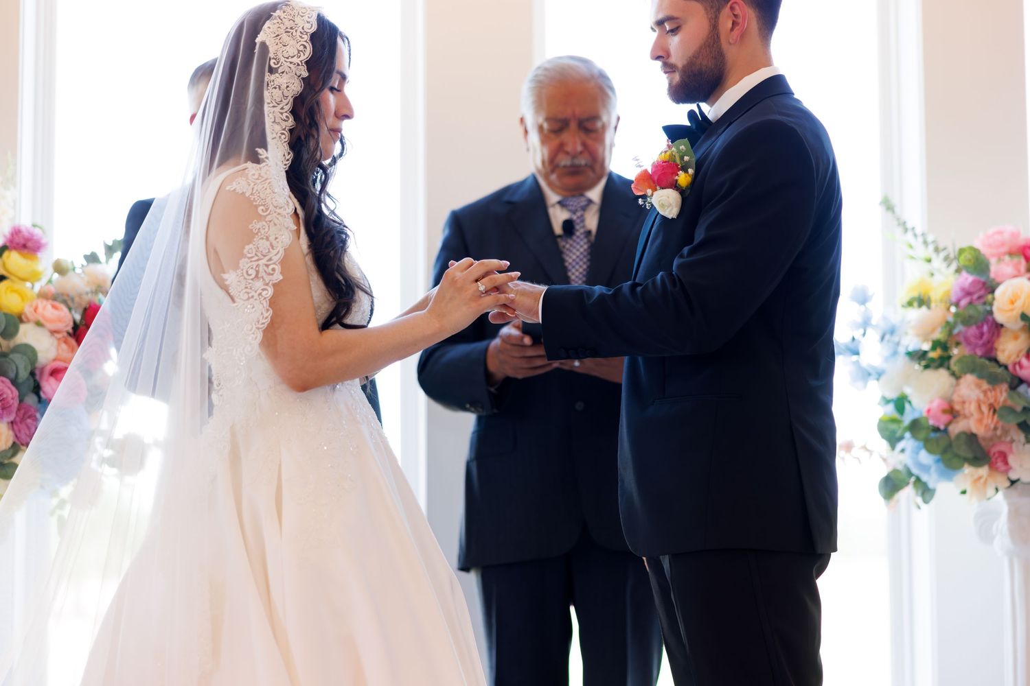 Wedding ceremony in progress with officiant and couple in bright indoor venue.