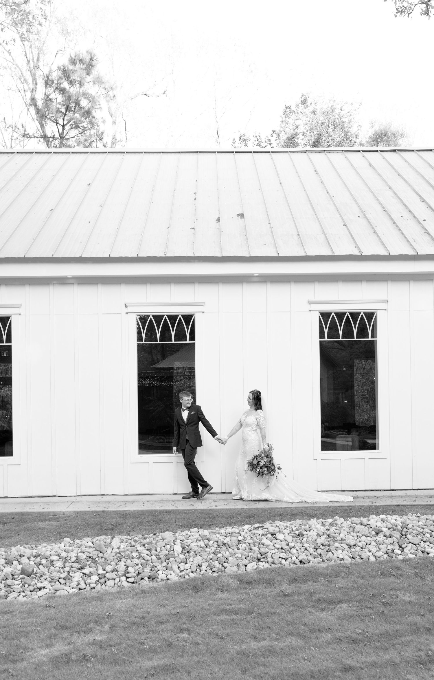 Bride and groom hold hands walking outside a white chapel venue on their wedding day.