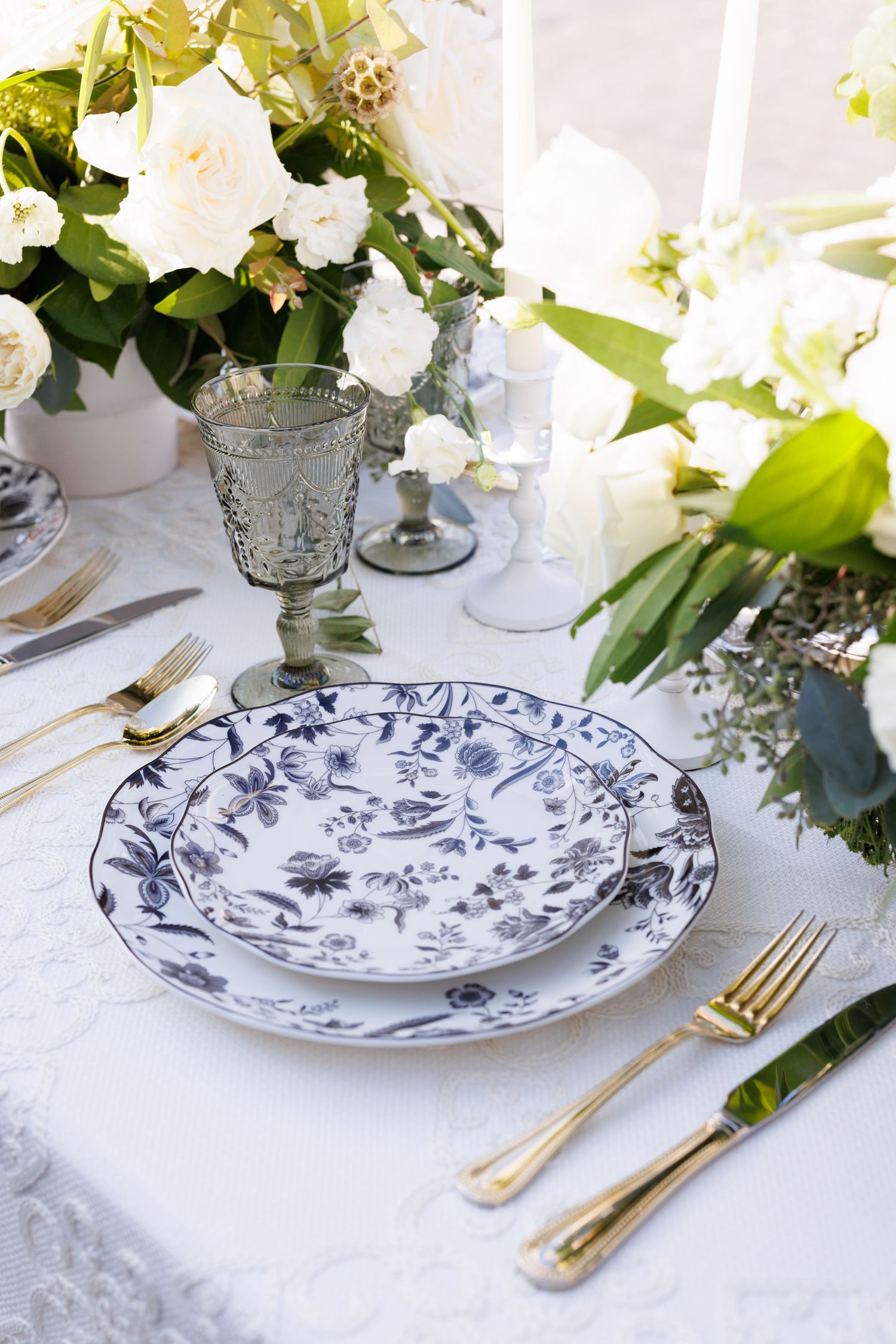 Elegant table setting with blue and white chinoiserie plates and gold flatware.