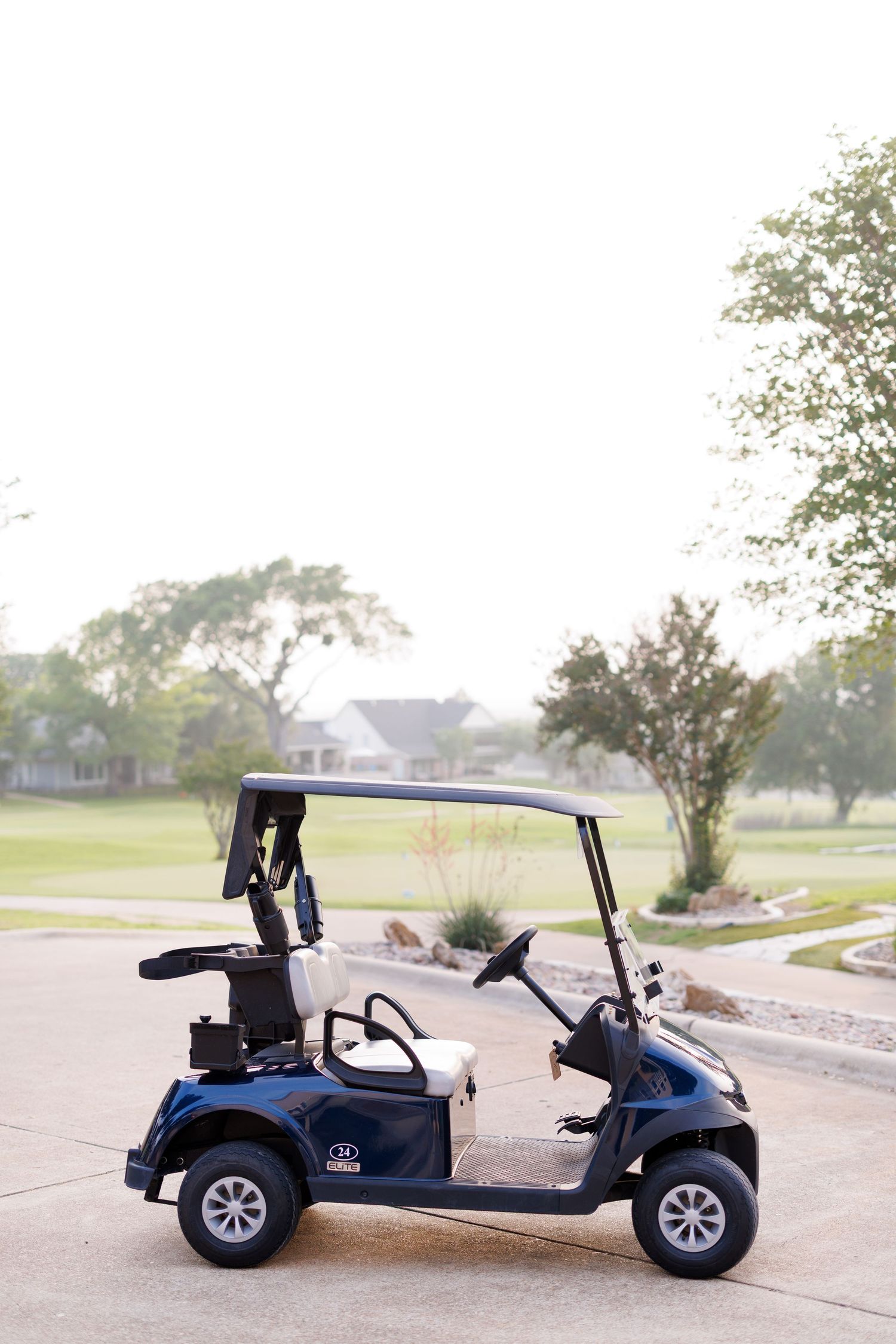 A navy blue golf cart parked on a path surrounded by lush greenery at a golf course venue.