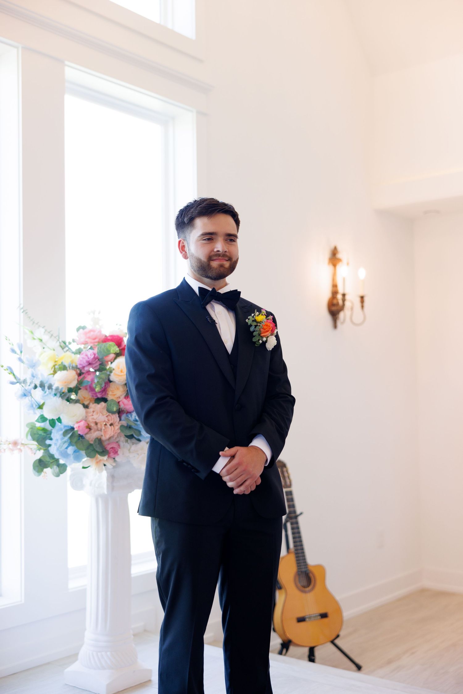 Bright white wedding venue interior with classical guitar and floral arrangements.