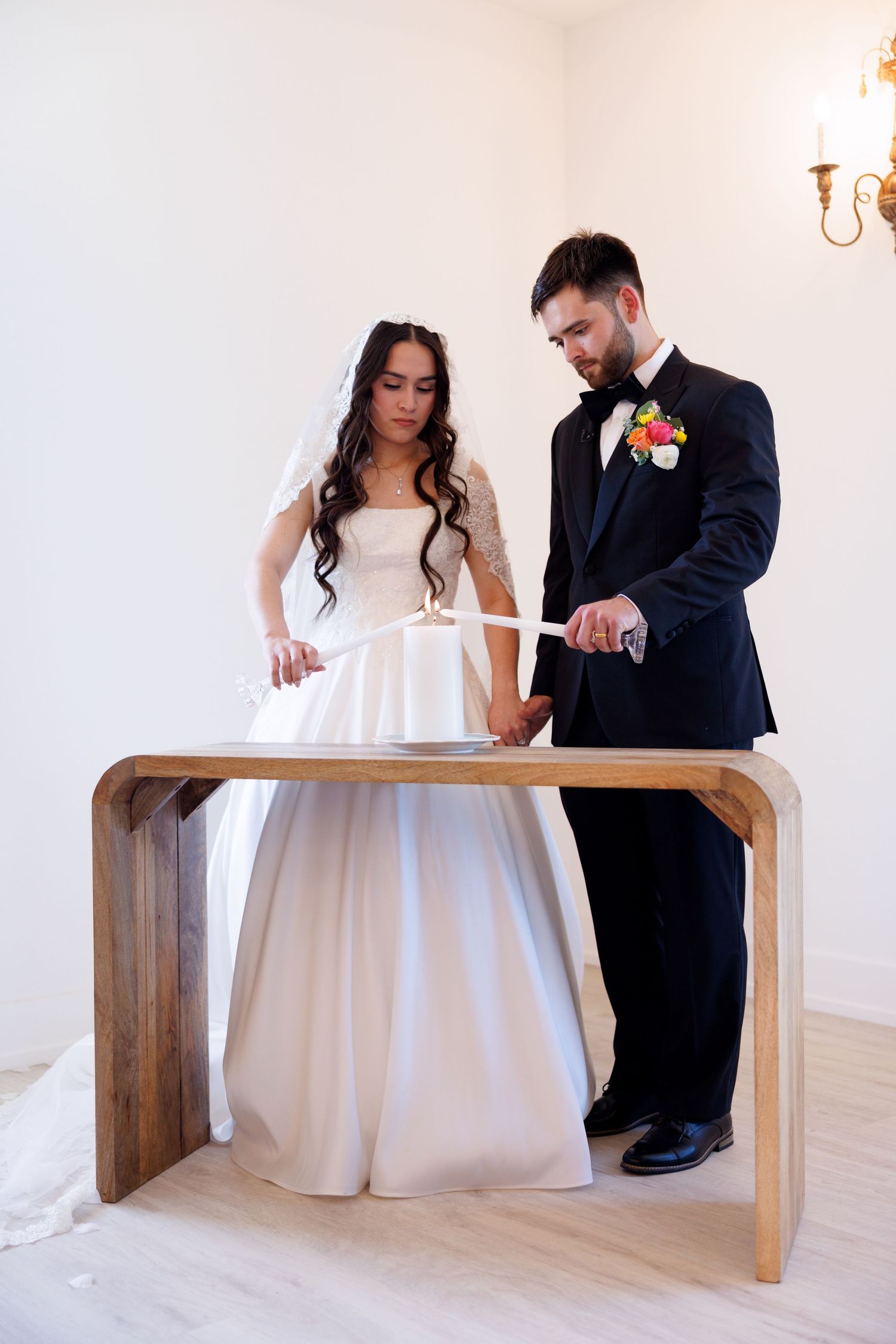 Bride and groom share a tender moment while signing documents on a modern wooden table.