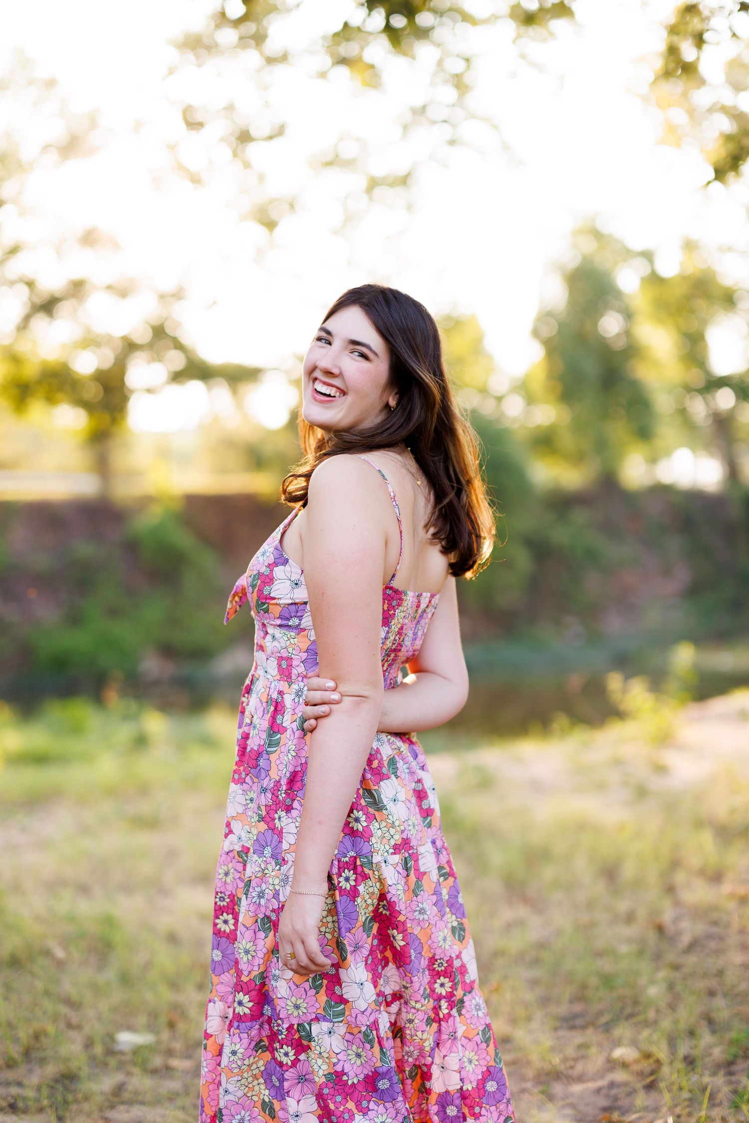 Joyful outdoor portrait session with a pink floral summer dress in natural lighting.
