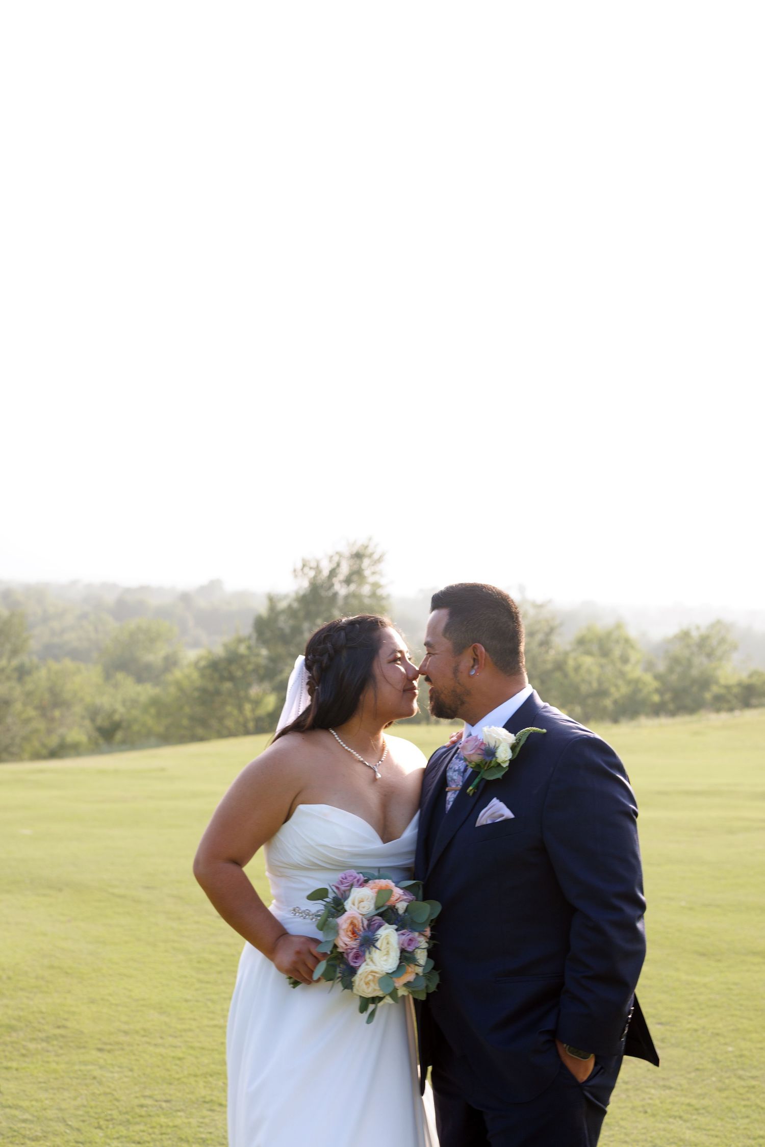 Bride and groom share a romantic almost-kiss on a golf course during their outdoor wedding portrait session.