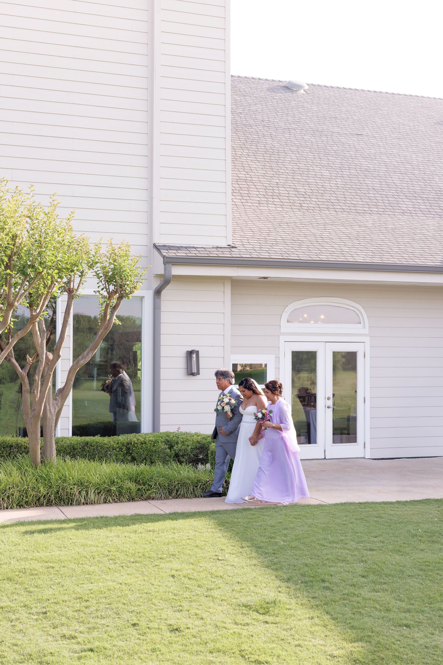 Bride and groom share a romantic moment outside an elegant white wedding venue surrounded by lush greenery.