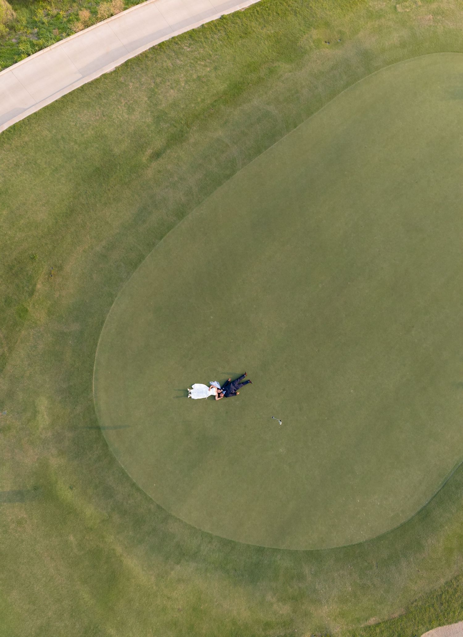 Aerial drone view of a golfer putting on a circular green golf course surrounded by manicured fairway grass.