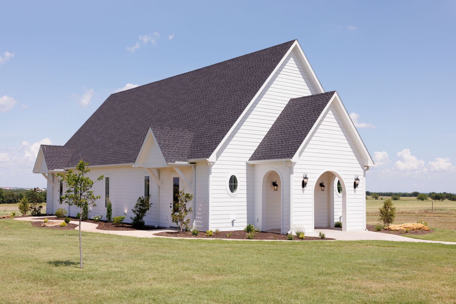 Row of white country chapel buildings with steeples against blue sky.
