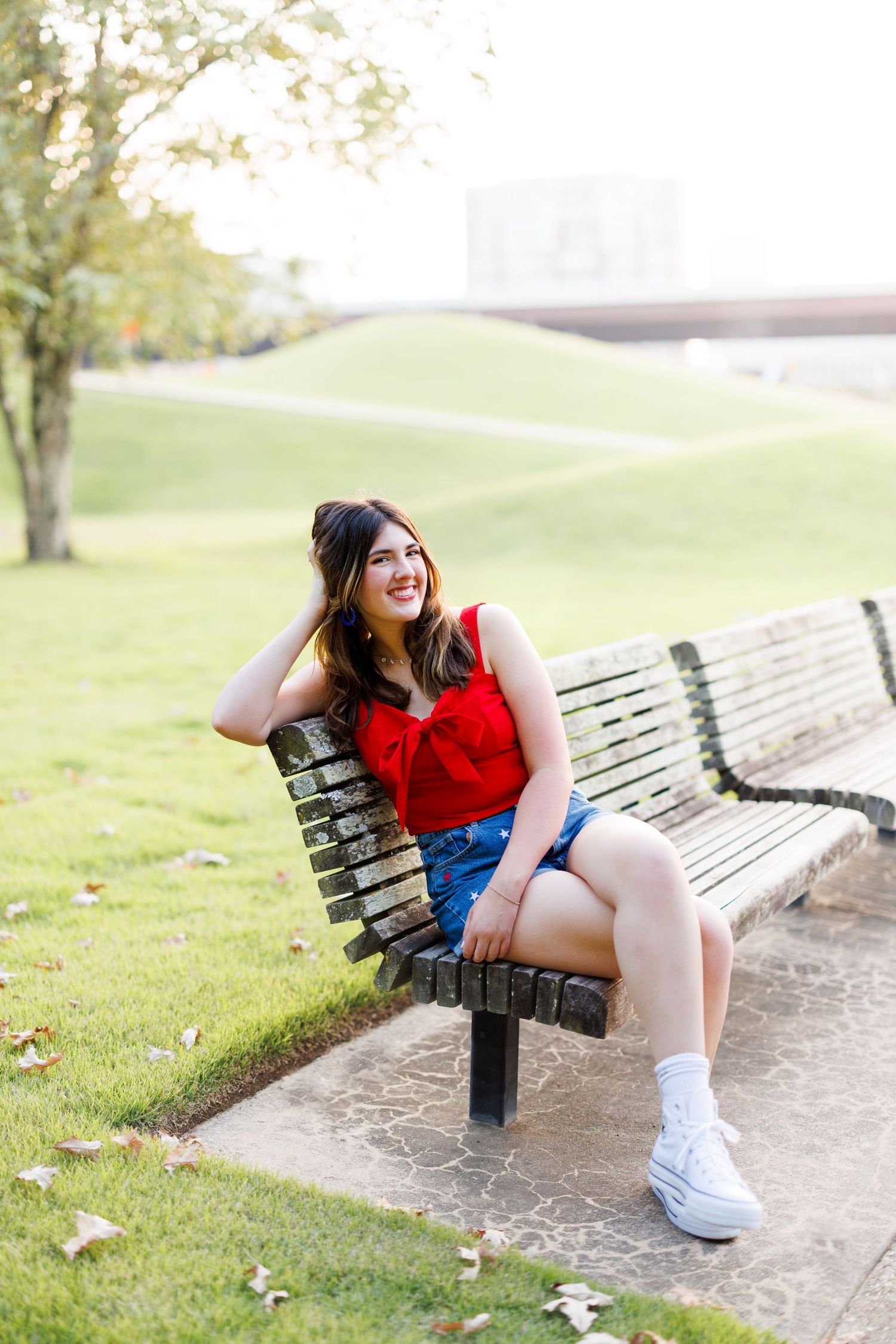 Person relaxing on wooden park bench wearing casual summer attire.