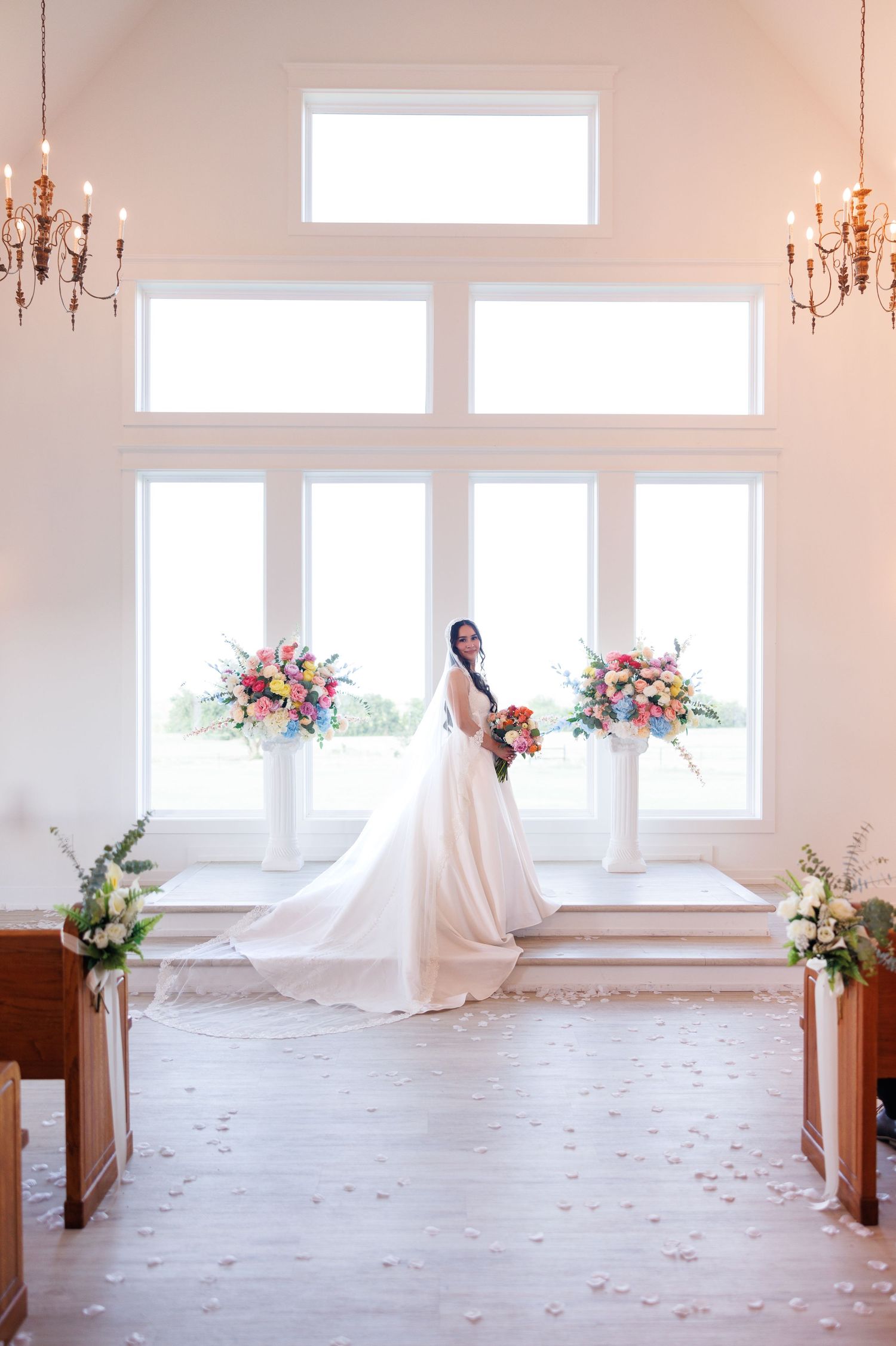 Ethereal bridal portraits in bright white chapel with scattered rose petals.