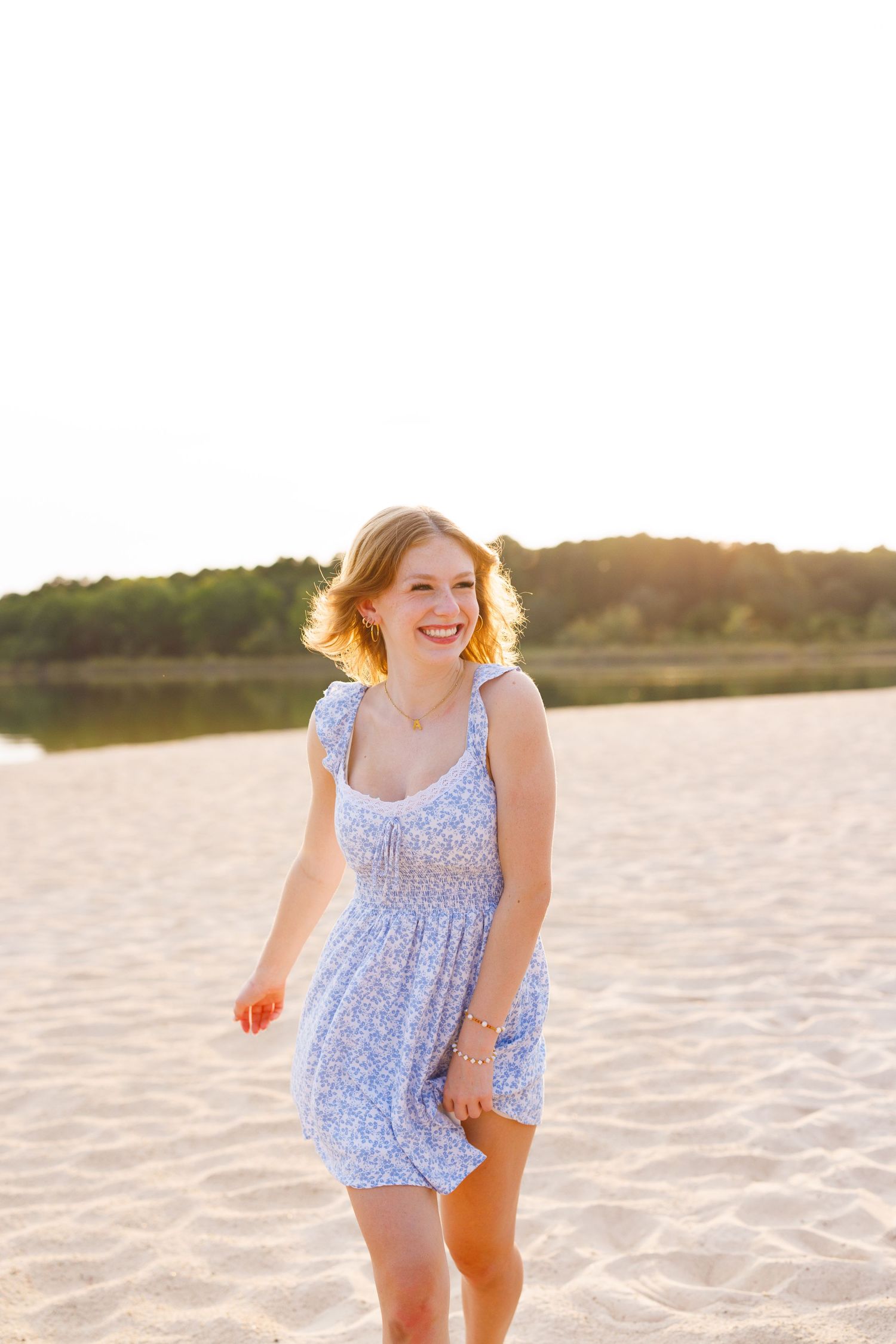 Candid moment in blue sundress on beach with golden sunset lighting.