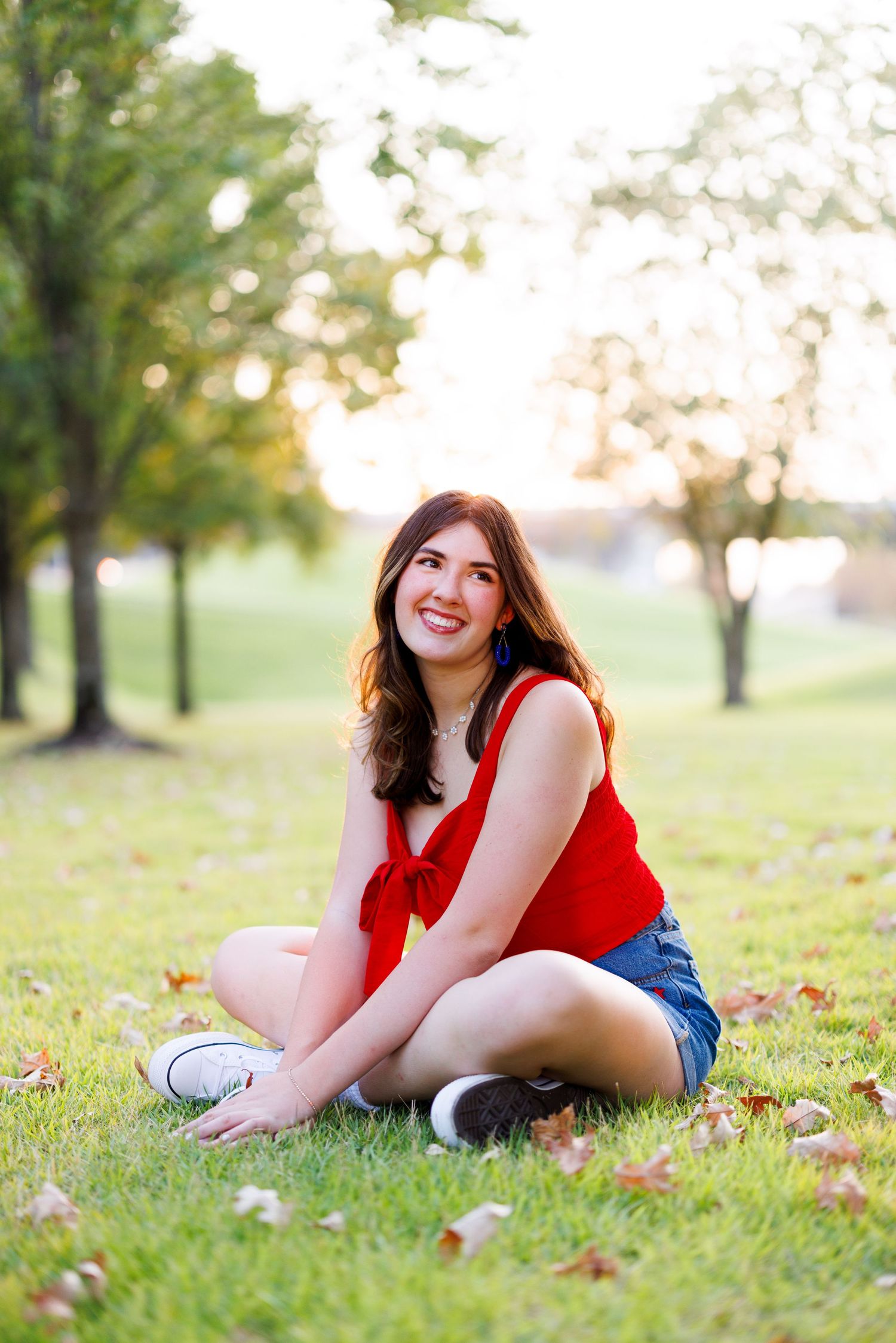 Casual outdoor photography session on grass wearing red top and denim.
