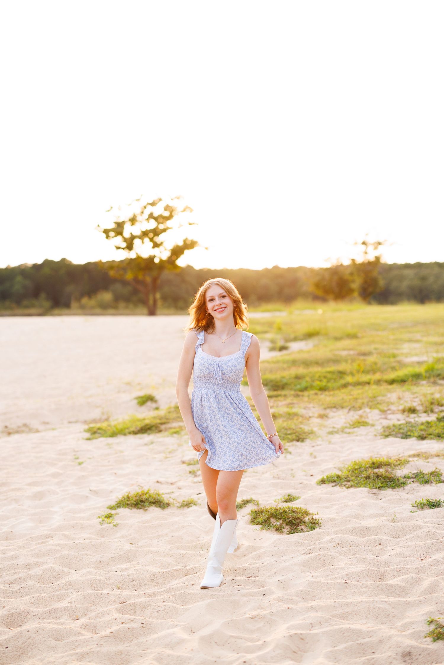 Person in a floral dress skipping joyfully on a sandy beach at sunset.
