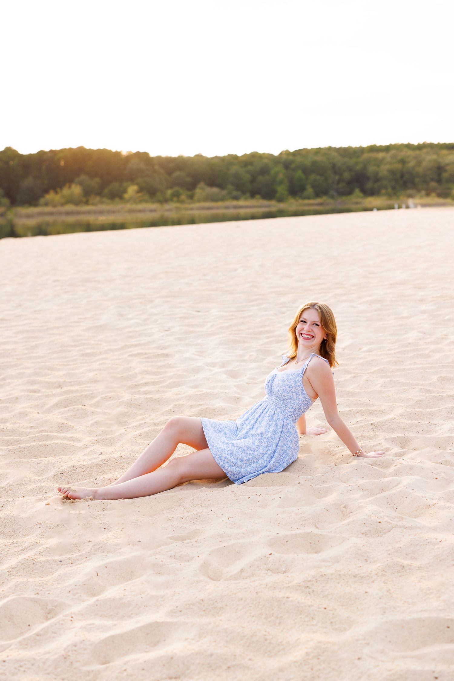 Relaxed beach pose in light blue sundress during golden hour.